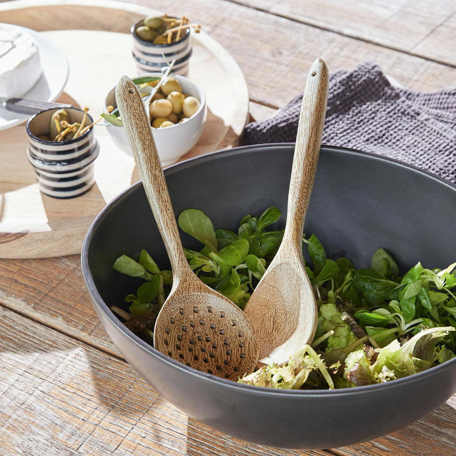 Salatbesteck Helier Schwarze Holzschüssel mit grünem Salat und Holzsalatbesteck auf rustikalem Holztisch