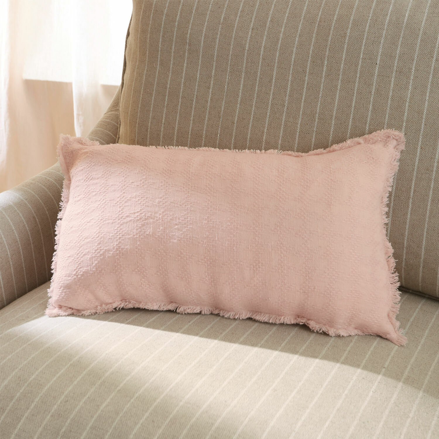 Kissenhülle Saavreda Rosa Dekokissen aus weichem Stoff auf beige gestreiftem Sofa für gemütliches Wohnzimmer