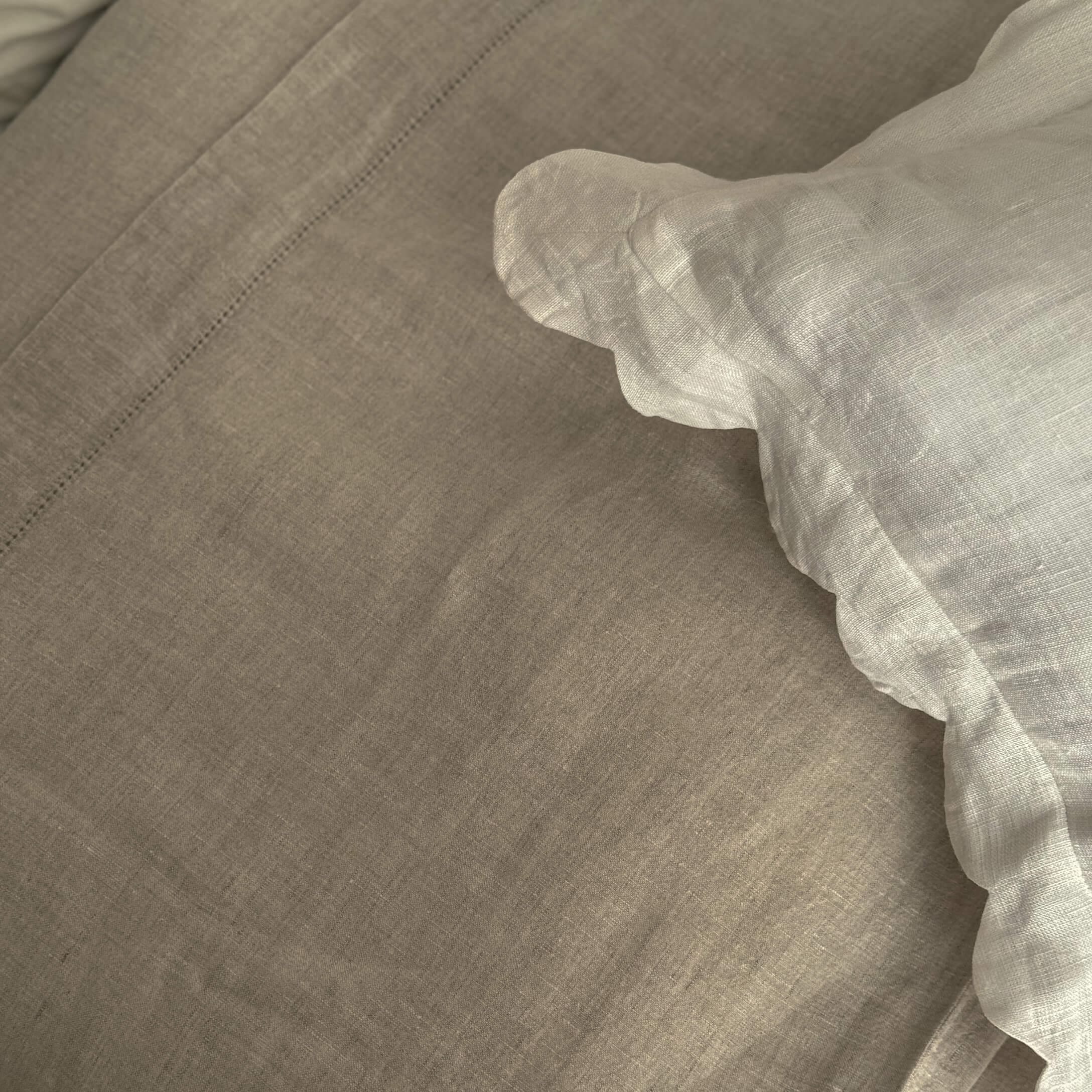 Beige Leinenbettwäsche mit weißem Rüschensaum, natürliche Stoffqualität für gemütliches Schlafzimmer