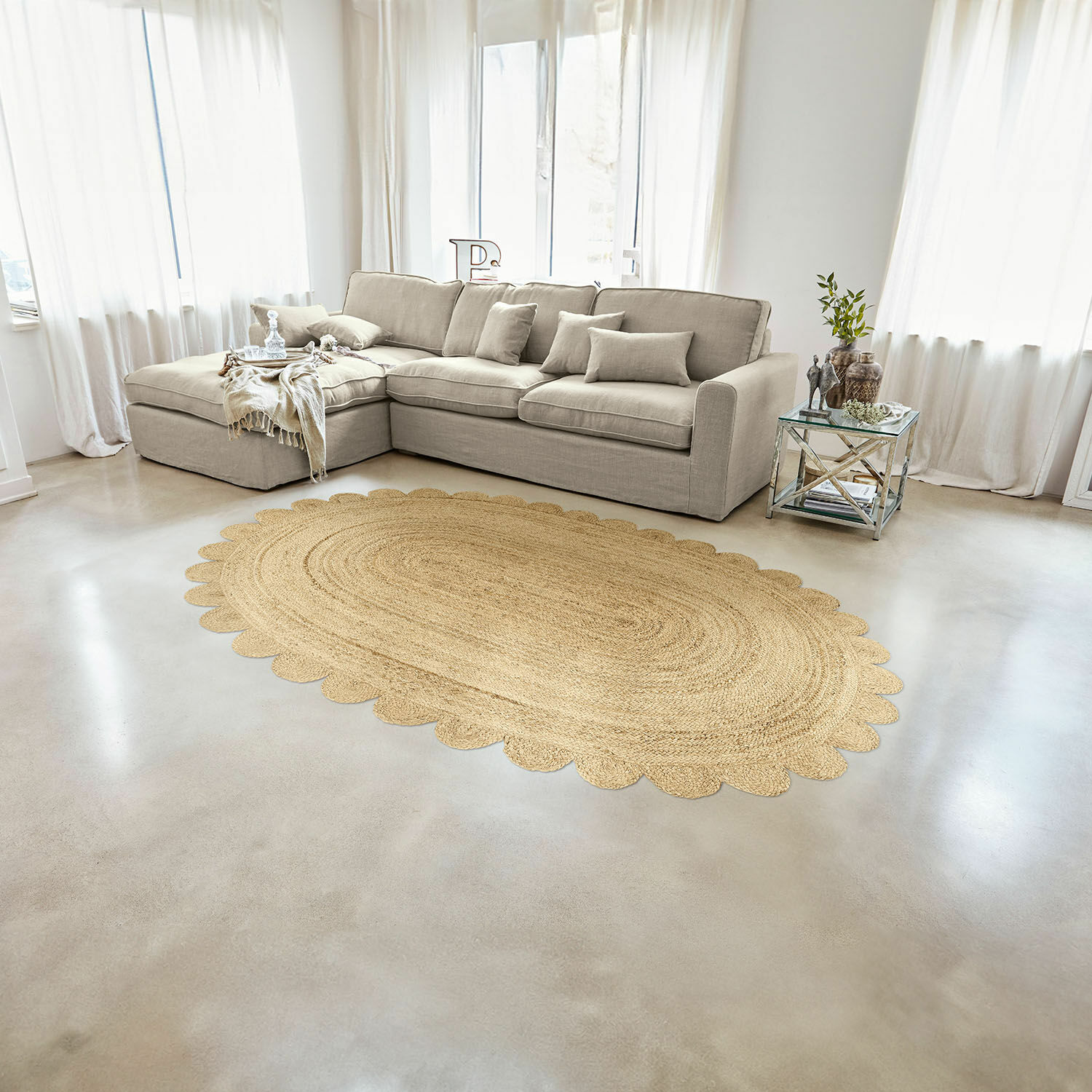 Teppich Ferce Ovaler Teppich aus Jute in Naturfarbe mit gewelltem Rand im hellen Wohnzimmer mit beigem Sofa