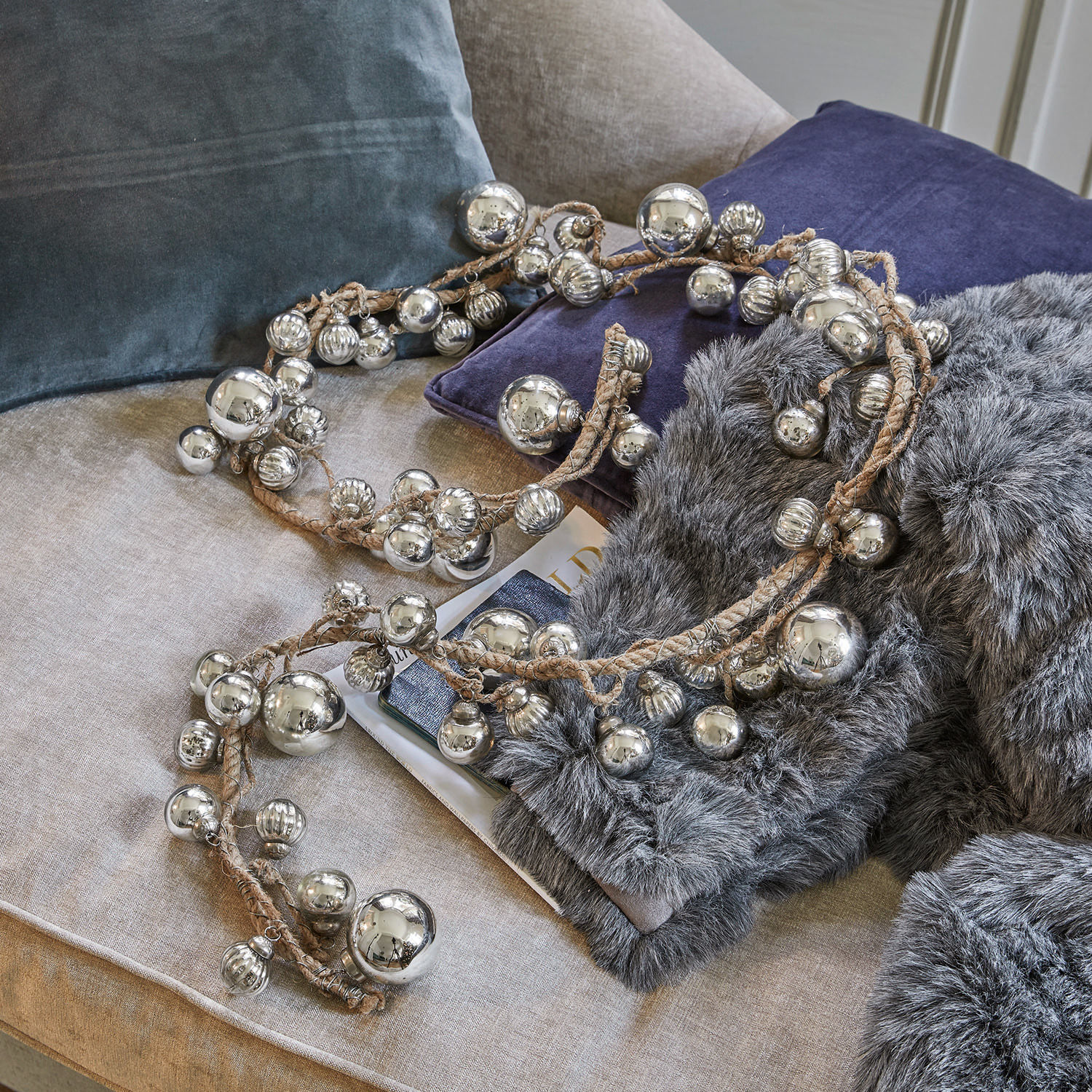 Girlande Pearls Dekorative Kette mit silbernen Metallkugeln an Leinenkordel auf Sofa mit Kissen