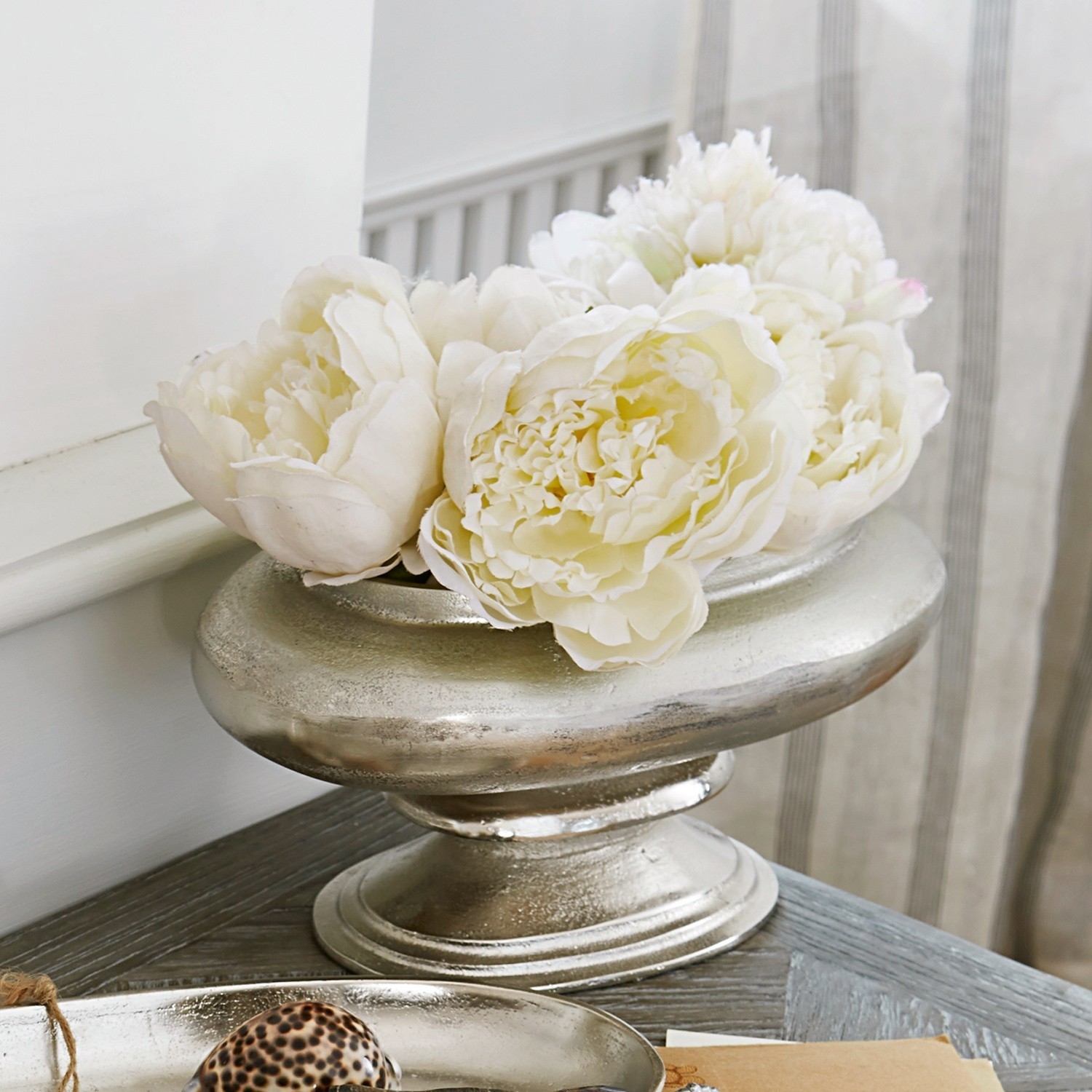 Silberne Metall-Dekoschale mit weißen Blumen auf Holztisch im Wohnzimmer