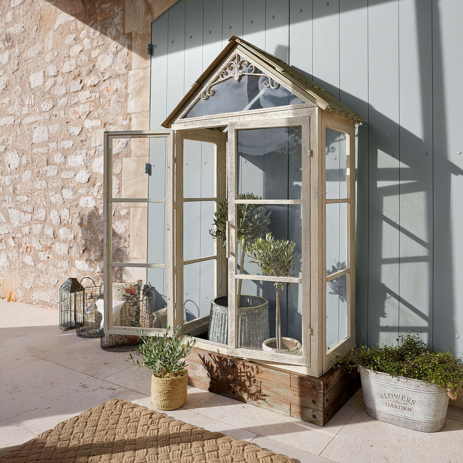 Kleine Garten-Gewächshaus aus cremefarbenem Metall auf Holzsockel zur Pflanzenzucht im Freien
