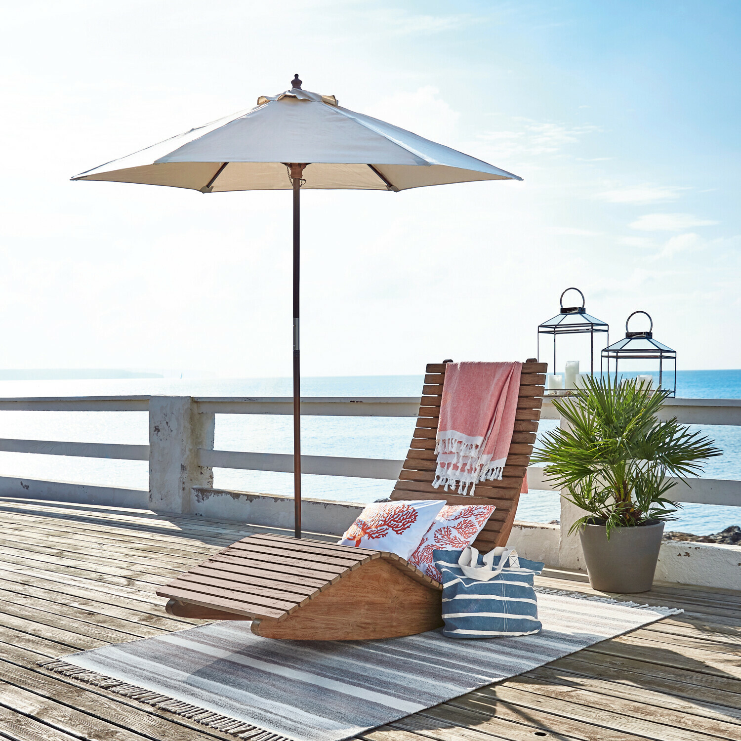 Sonnenschirm Enfield Holzliege auf Terrasse mit weißem Sonnenschirm und dekorativen Kissen, ideal für Sommer und Garten