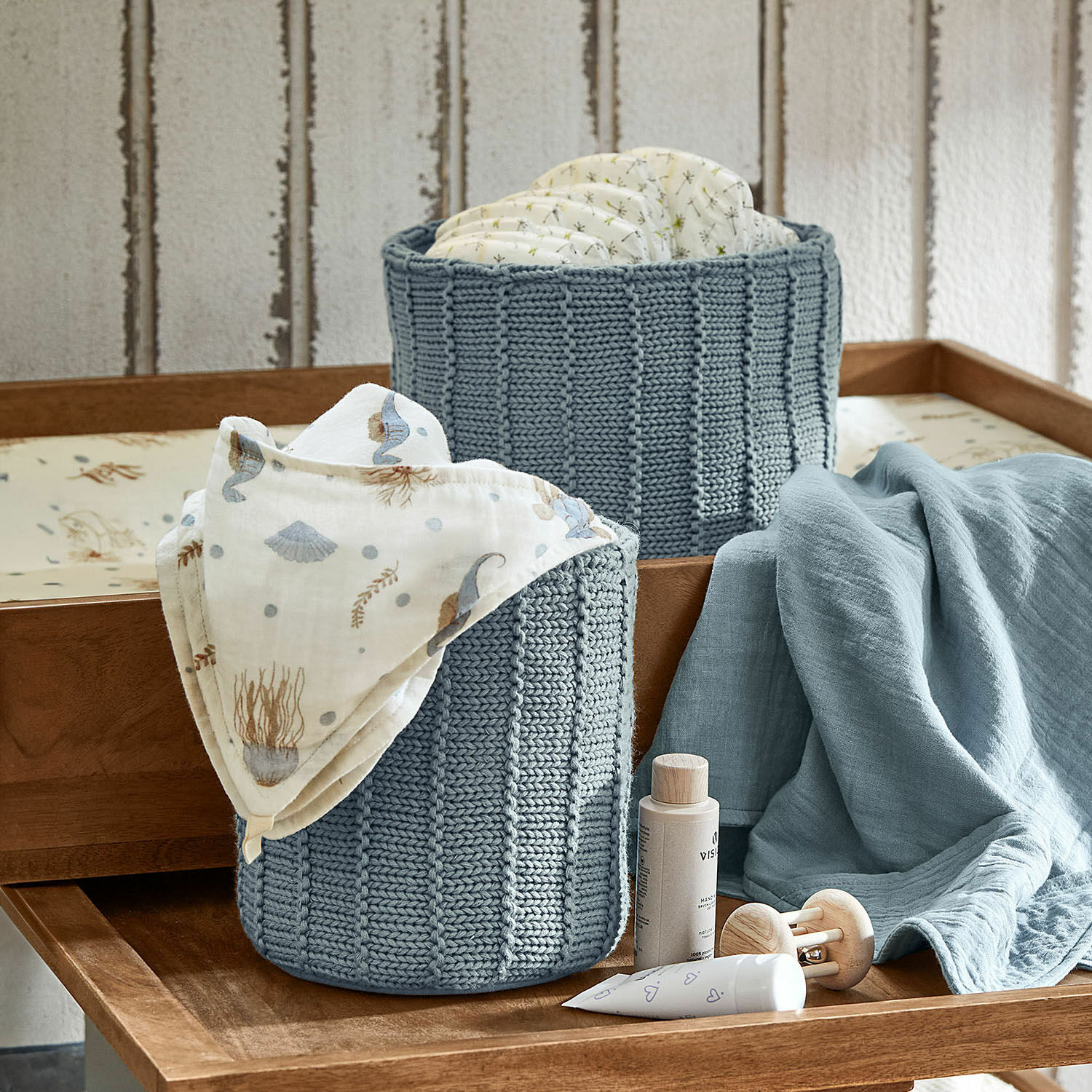 Box 2er Set Fiorenzo Zwei blaue gestrickte Körbe für Windeln und Babyzubehör auf einem Holzwickeltisch