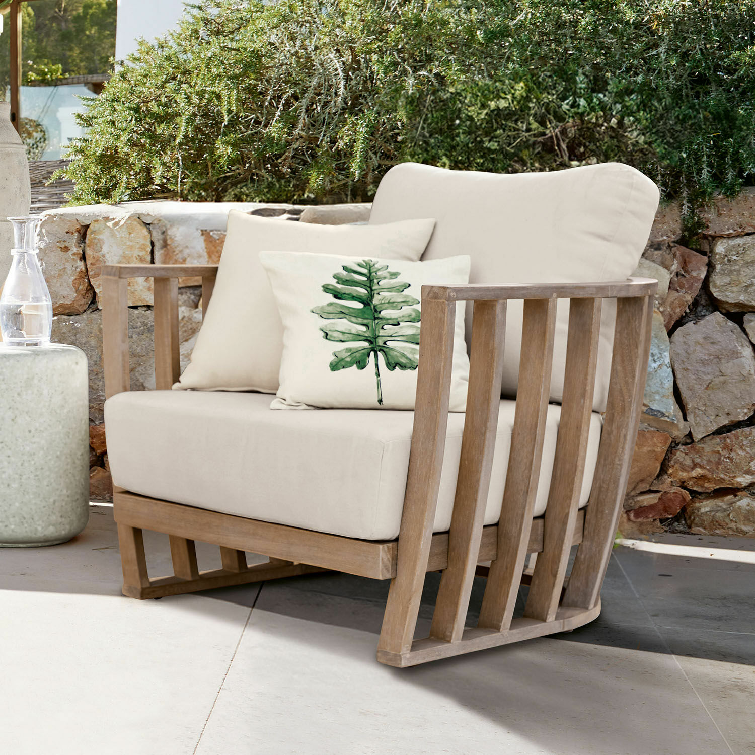 Sessel FSC®-100% Vézère Gartenfauteuil mit hellbeigem Stoffbezug und Holzrahmen, dekoriert mit Kissen mit grünem Blattmotiv