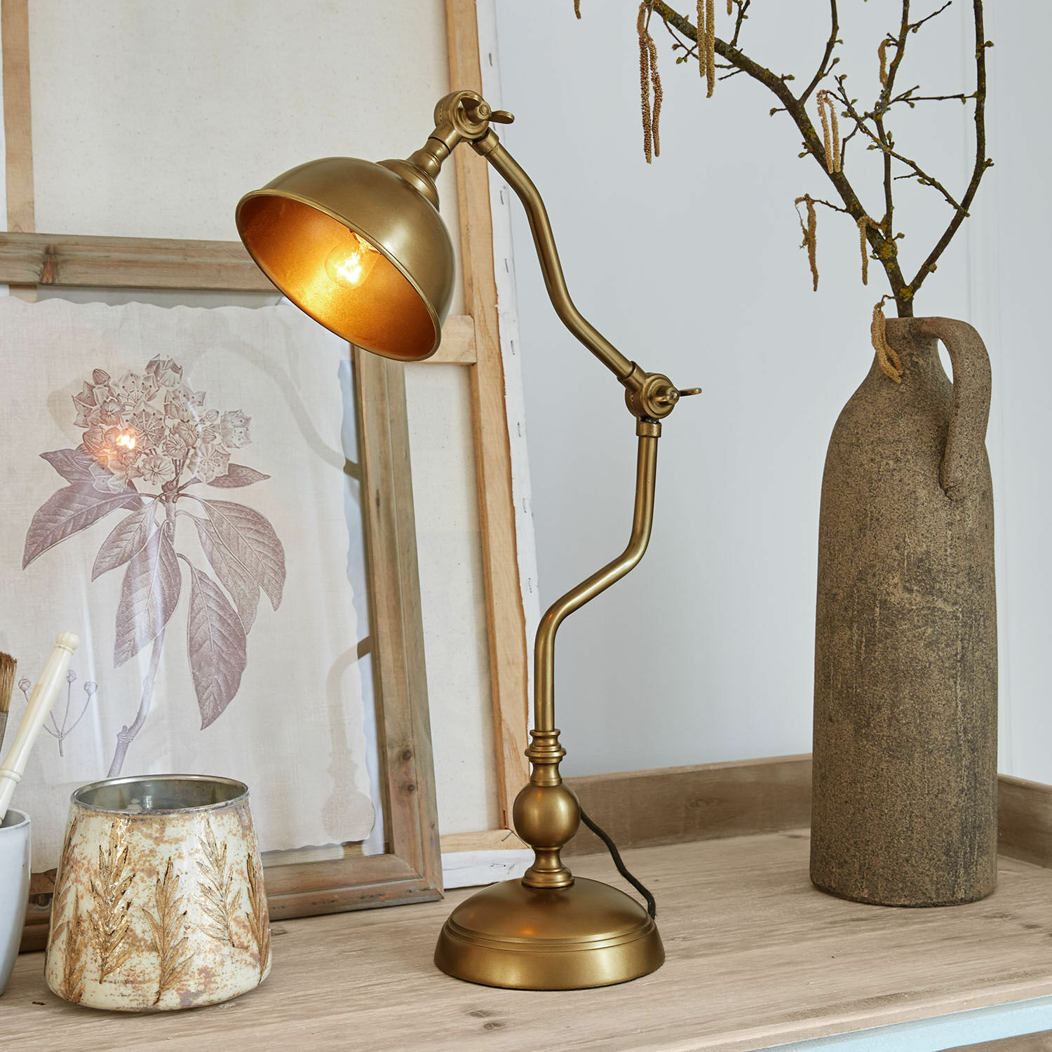 Tischlampe Harrowden Goldfarbene Metall-Tischlampe mit verstellbarem Arm auf Holzplatte mit Dekorationen