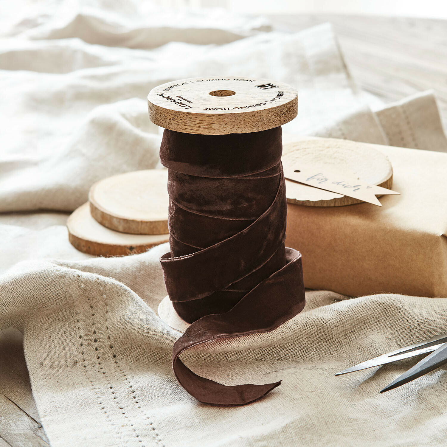 Braunes Samtband auf Holzspule auf natürlichem Leinenstoff für Dekoration und Basteln