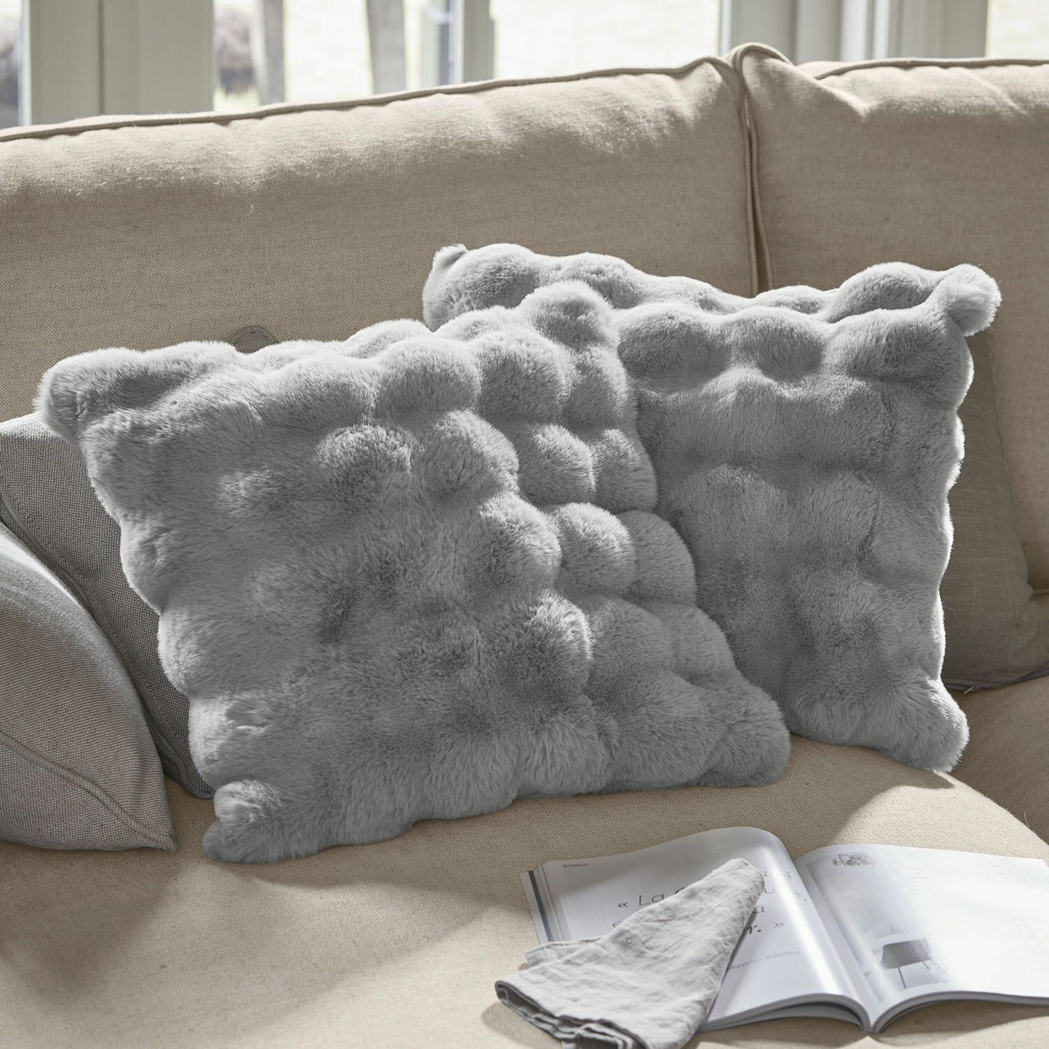 Kissenhülle 2er Set Zalina Weiche graue Dekokissen aus Fellimitat auf beigem Sofa, ideal für gemütliches Wohnzimmer