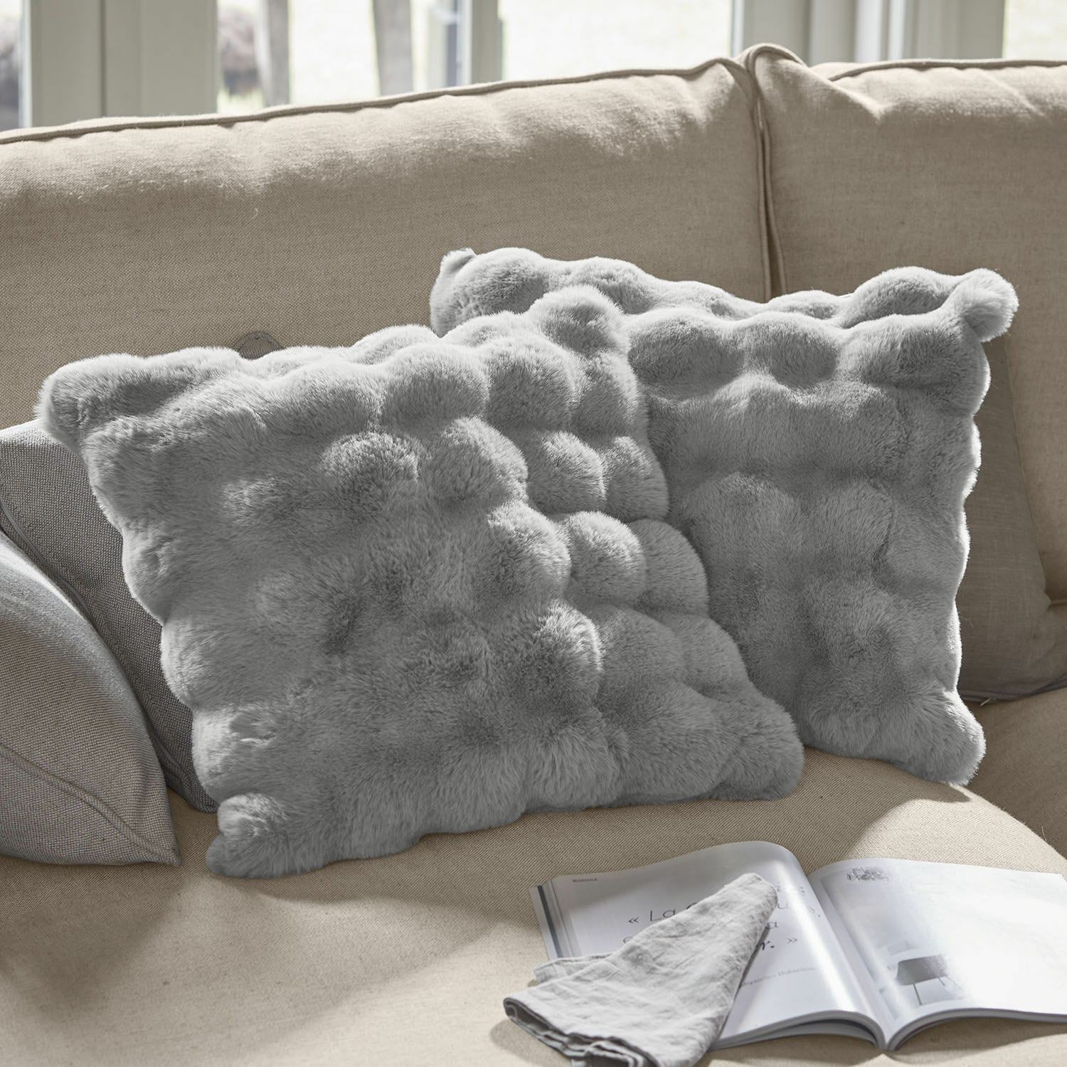 Kissenhülle 2er Set Zalina Weiche graue Dekokissen aus Fellimitat auf beigem Sofa, ideal für gemütliches Wohnzimmer