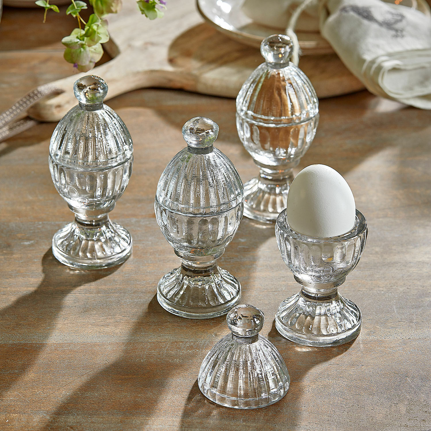 Eierbecher 4er Set Uvirel Transparente Glas-Eierbecher mit Deckeln auf Holztisch für die Küchendekoration