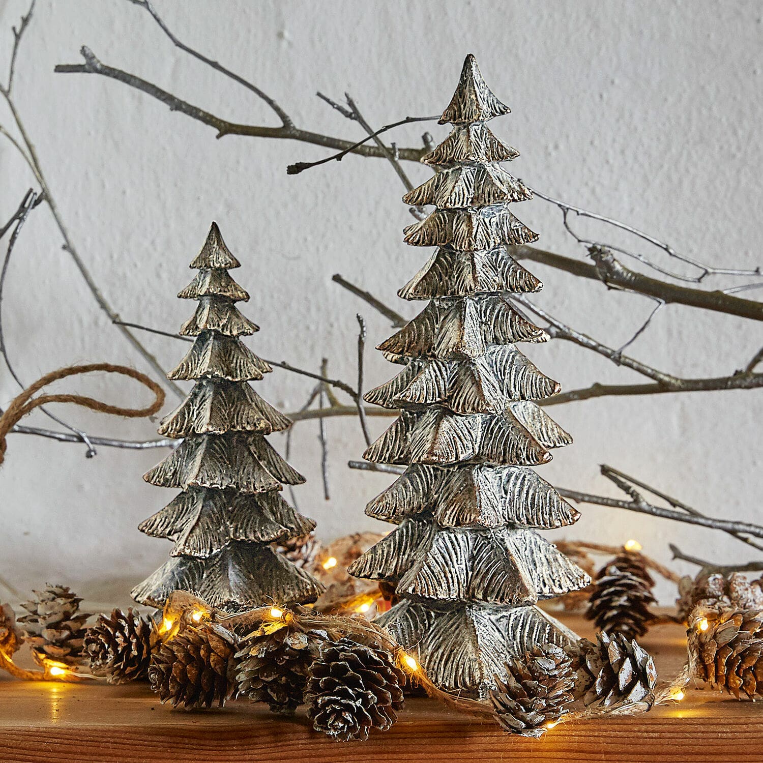 Deko-Baum 2er Set Calavi Dekorative silberne Metall-Weihnachtsbäume auf Holztisch mit Lichterkette und Tannenzapfen