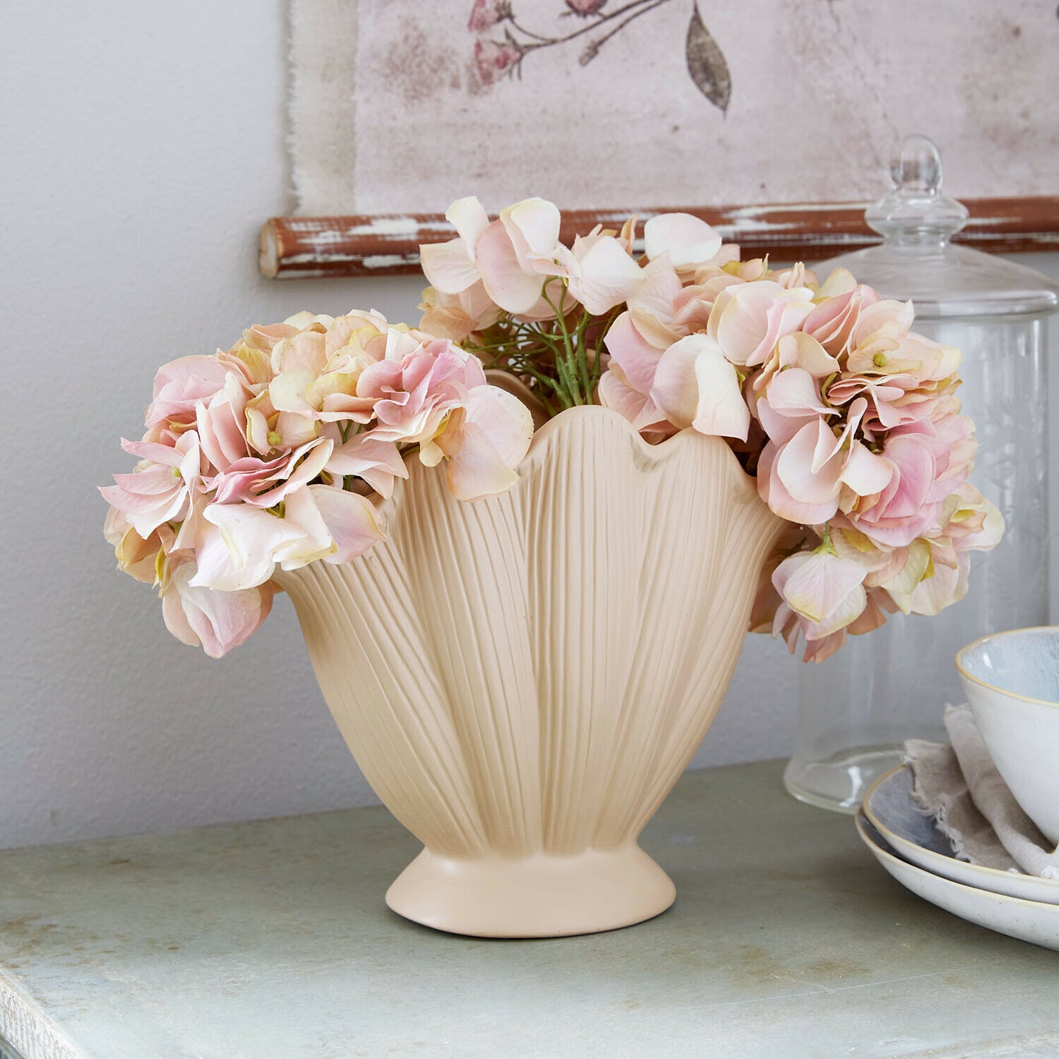 Vase Nuvienne Beige Keramikvase mit Blattstruktur und rosa Dekoblumen auf einem Tisch