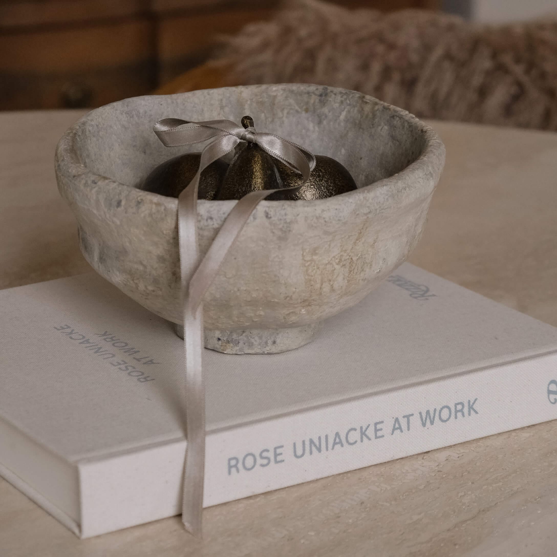 Dekorative graue Steinschale mit Metallornament und Band auf einem Buch auf dem Tisch