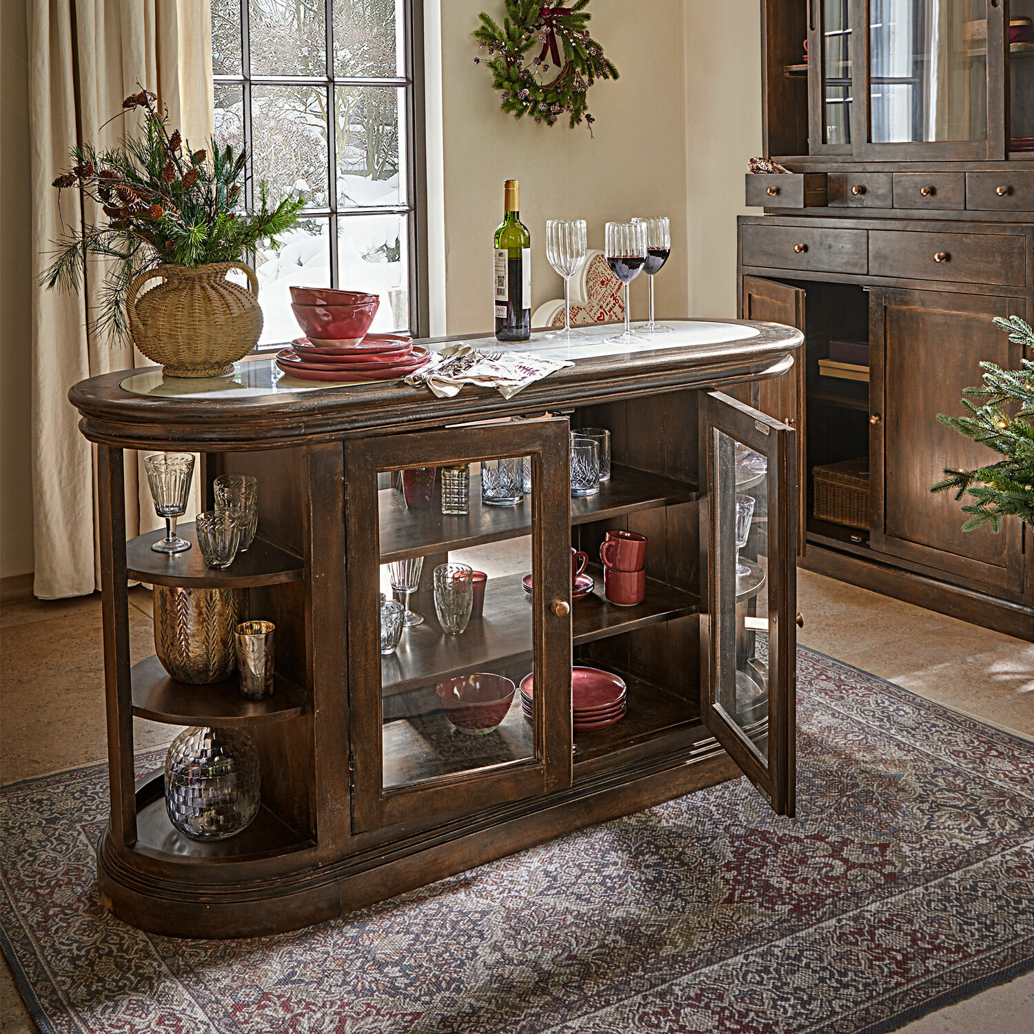 Dunkler Holzschrank mit Glastüren und Regalen, Dekoration und Geschirr im gemütlichen Wohnzimmer