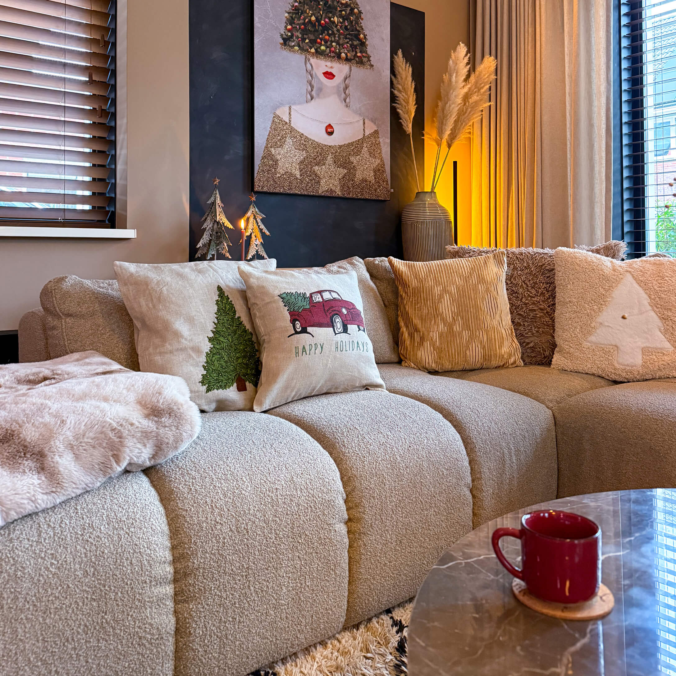 Beige Sofa mit weihnachtlichen Kissen und rotem Becher auf Marmor-Couchtisch im gemütlichen Wohnzimmer