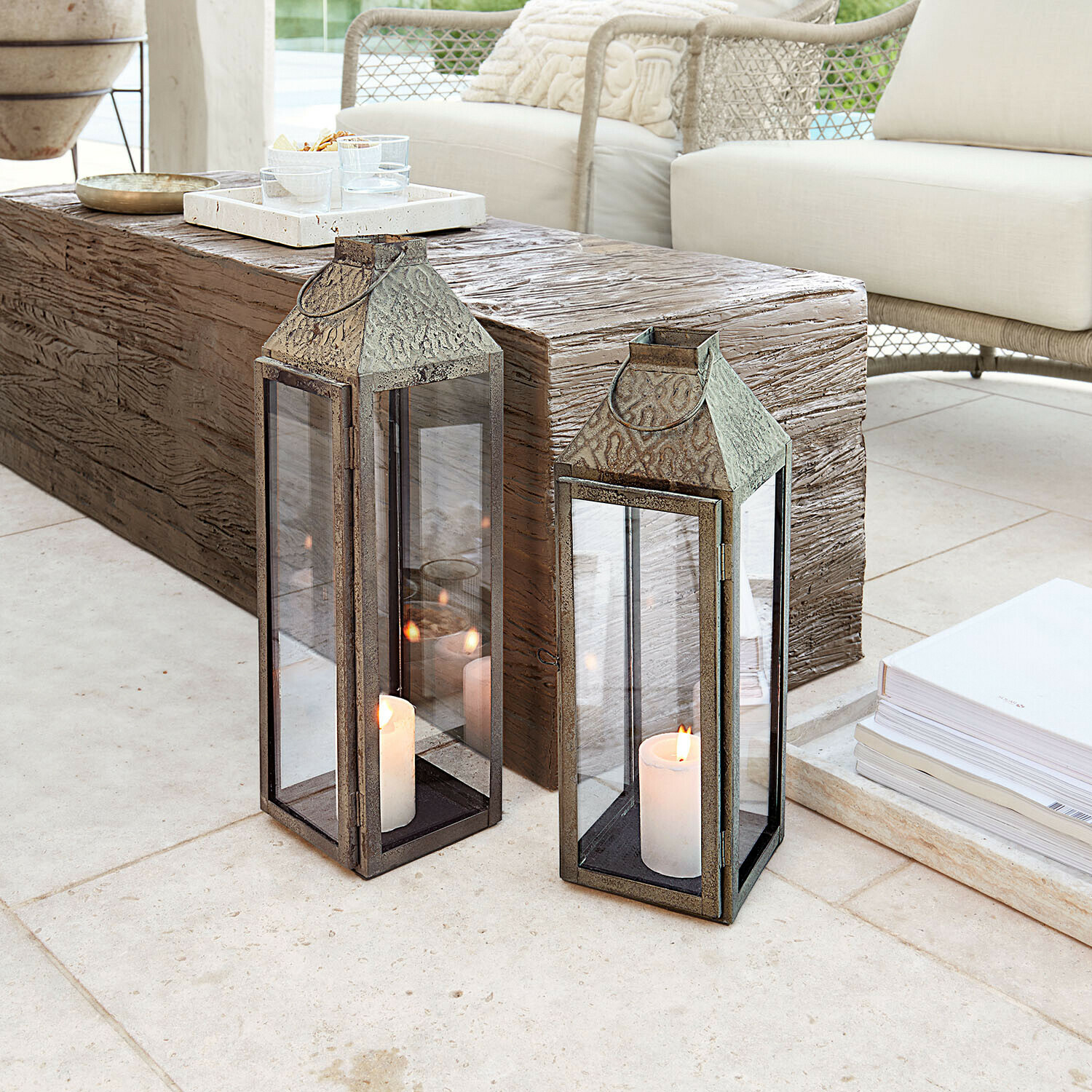 Zwei Metalllaternen mit weißen Kerzen auf hellem Boden in modernem Wohnzimmer