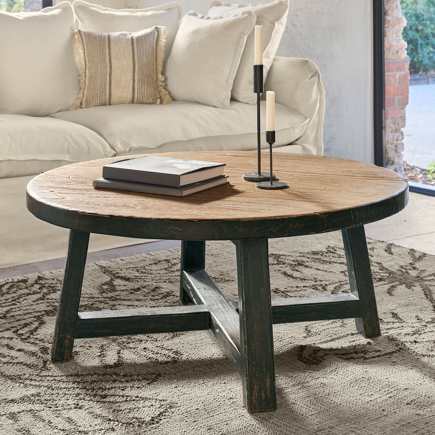 Couchtisch Gorivel Runder Couchtisch aus Holz in Natur- und Schwarzfarben auf Teppich im Wohnzimmer