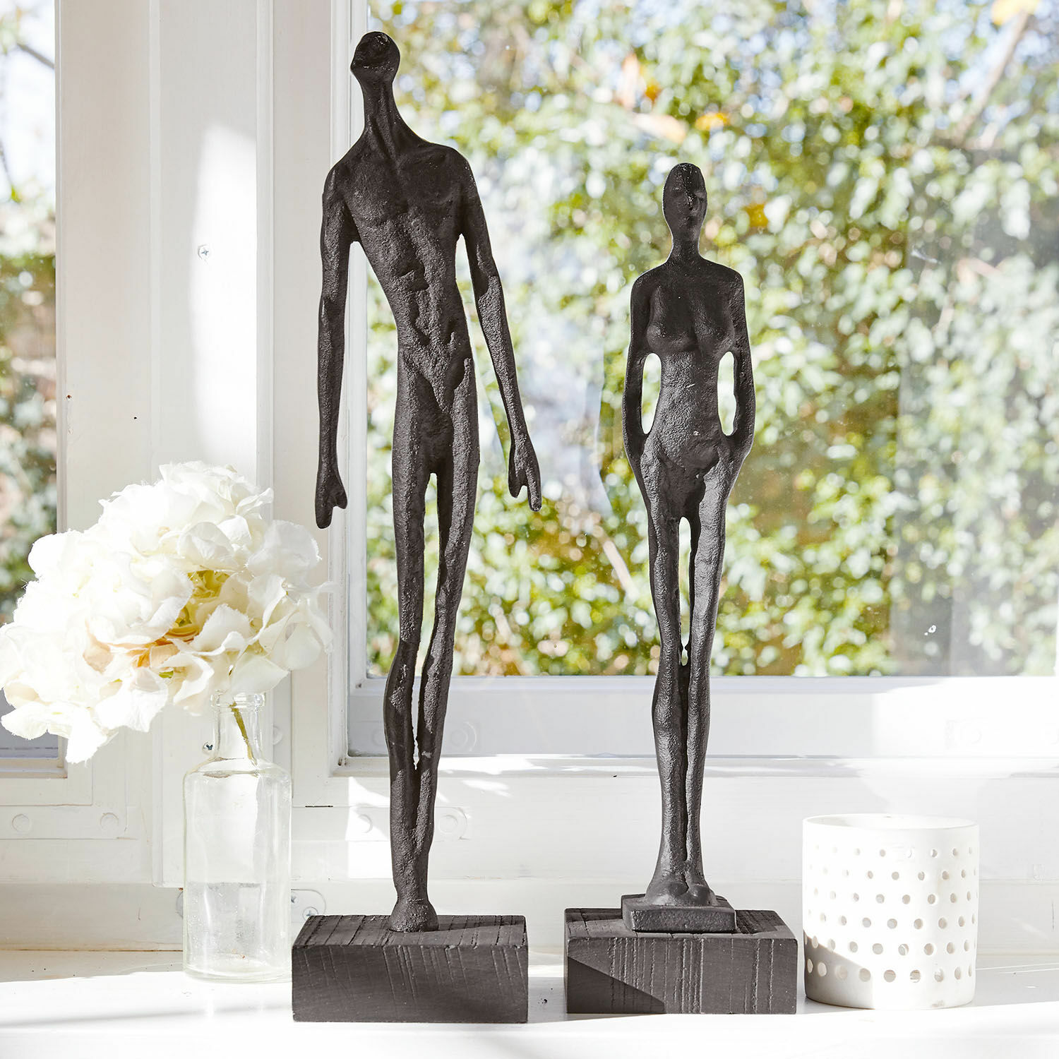 Figur 2er Set Perce Zwei schwarze Metallfiguren auf Holzsockeln vor hellem Fenster mit weißen Dekorationen