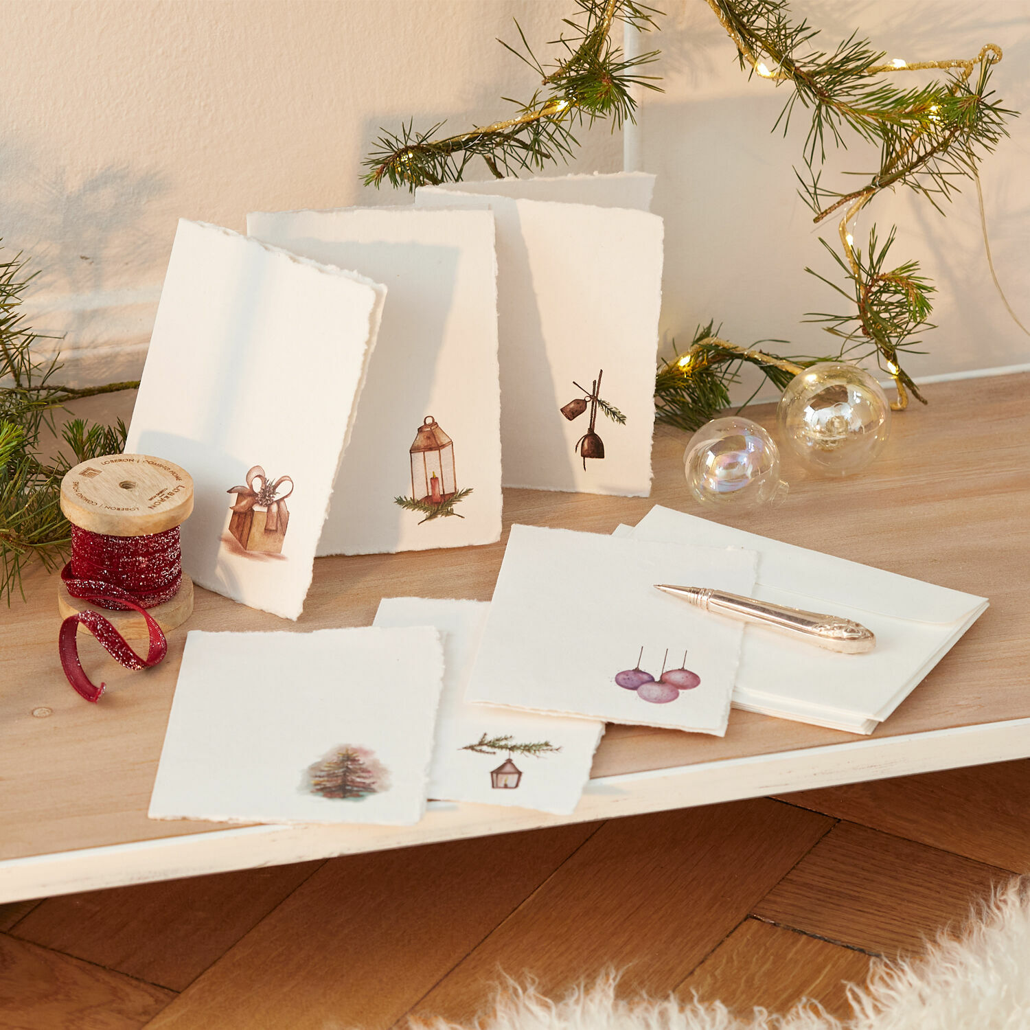 Grußkarten 6er Set Aeloria Set handgefertigter Weihnachtskarten aus Papier mit festlichen Motiven und rotem Dekoband auf Holztisch