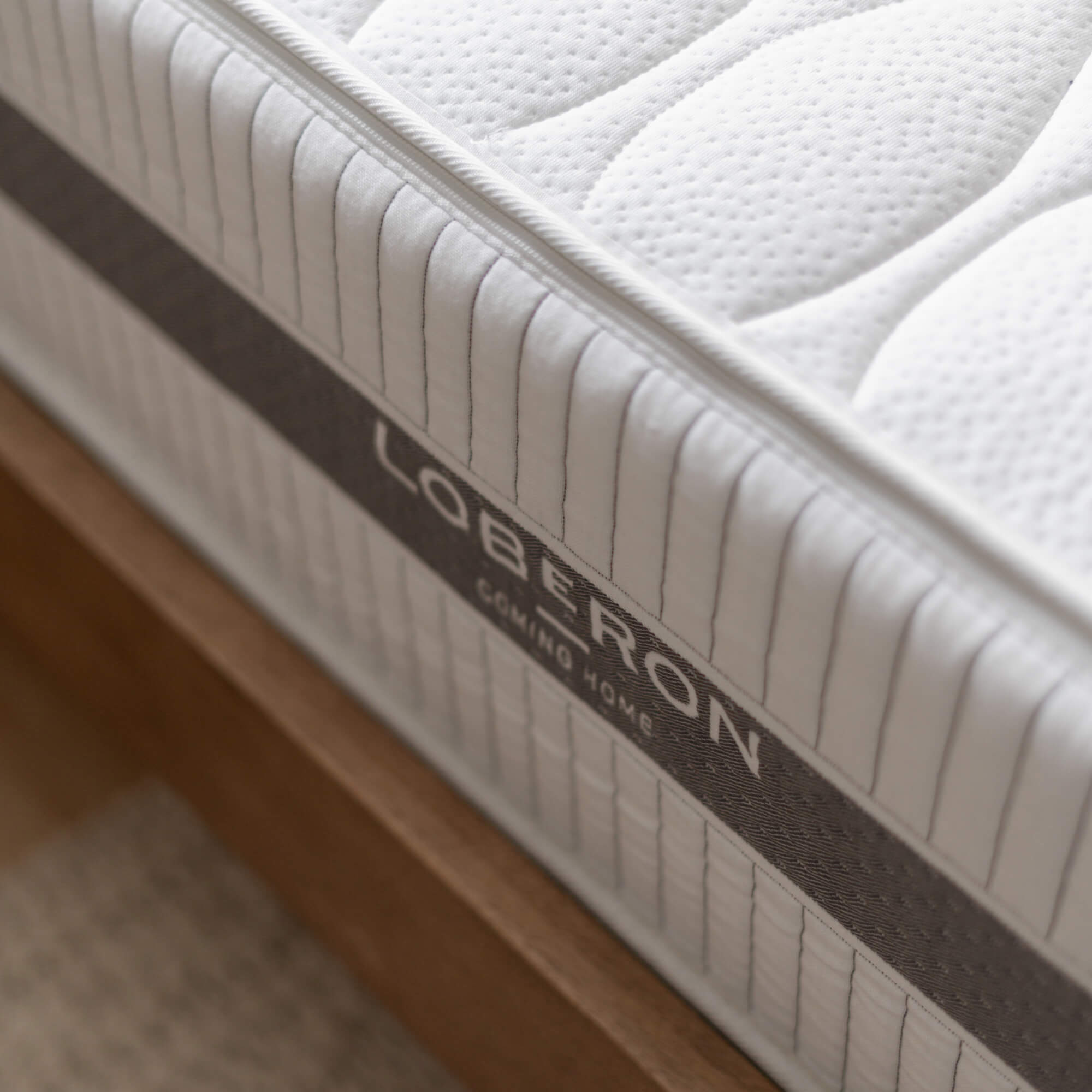 Weißer gesteppter Matratzenstoff mit grauem Rand auf Holzbettrahmen
