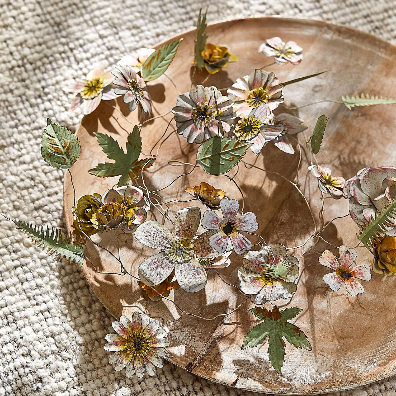 Dekorative Metallblumen und Blätter in Pastellfarben auf einem Holztablett, Wohnaccessoire