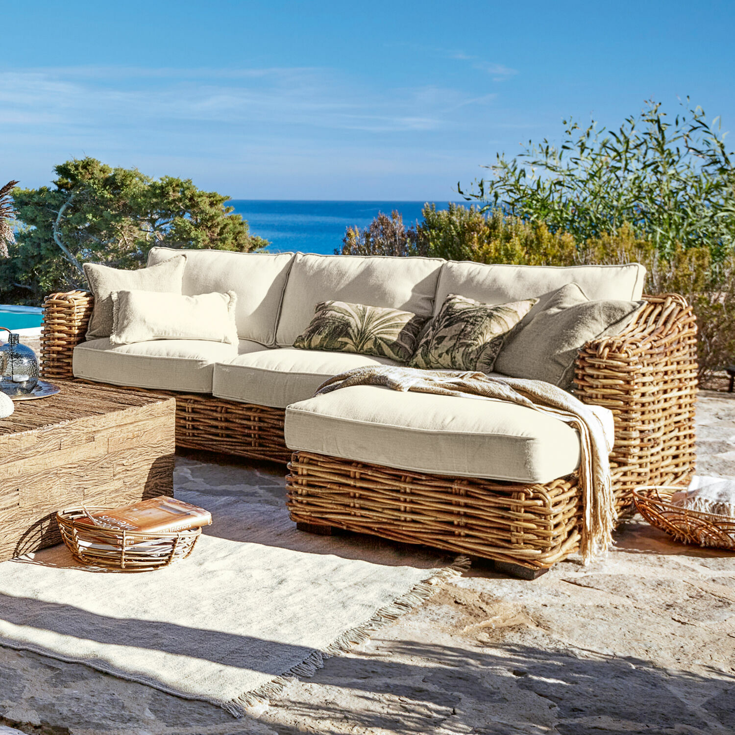 Sofa Villedieu Ecksofa aus Rattan mit cremefarbenen Kissen auf Terrasse mit Meerblick, Gartenmöbel