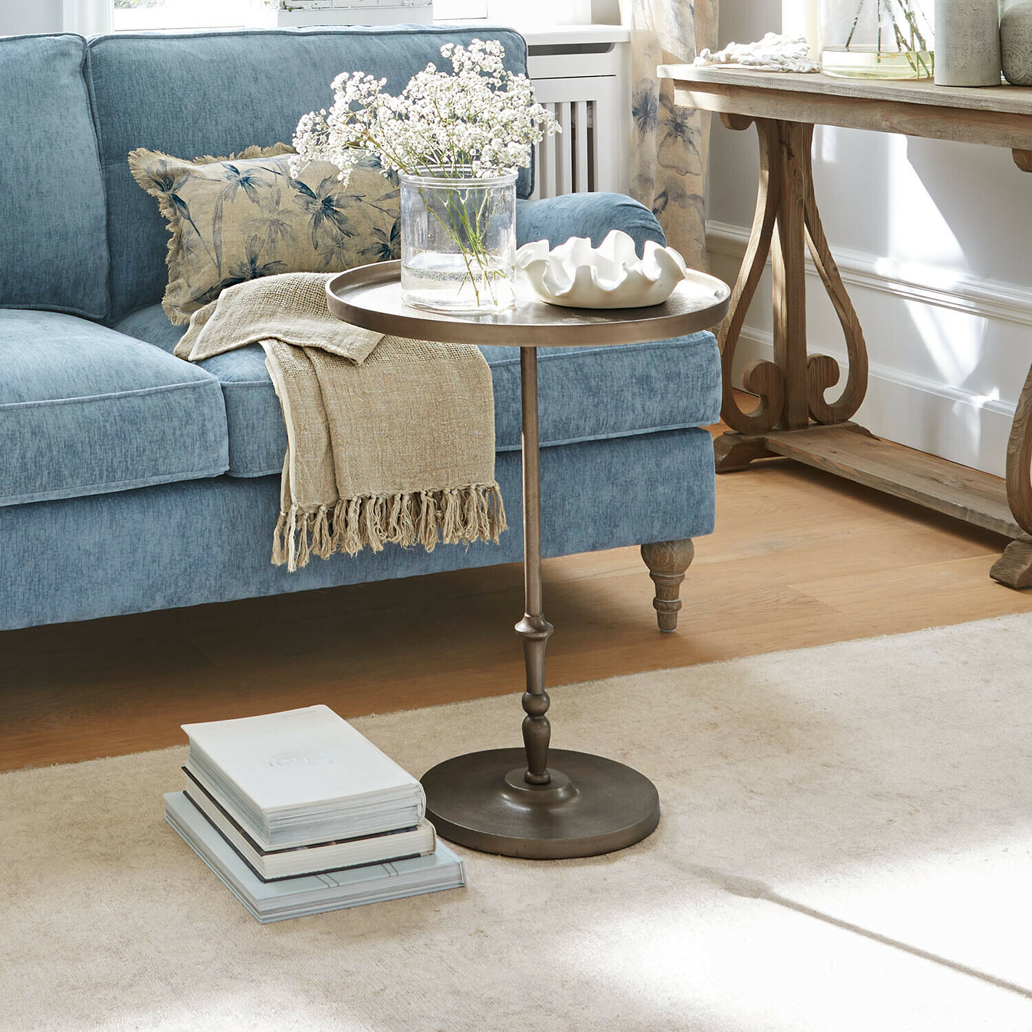 Runder Metall-Beistelltisch im Wohnzimmer mit blauem Sofa und dekorativer Decke