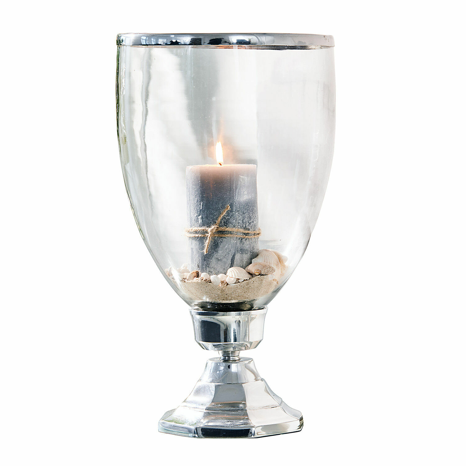 Glaswindlicht mit Metallfuß und grauer Kerze auf Sand und Muscheln, stilvolle Wohnraumdeko