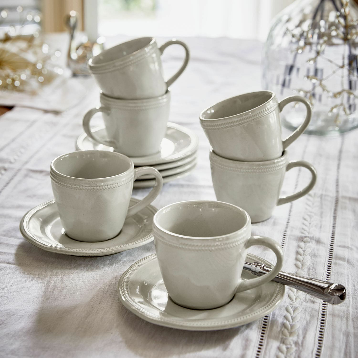 Tasse mit Untertasse 6er Set Norrvik Set aus weißen Keramiktassen mit Untertassen auf weißem Tischdecke für Kaffee und Tee