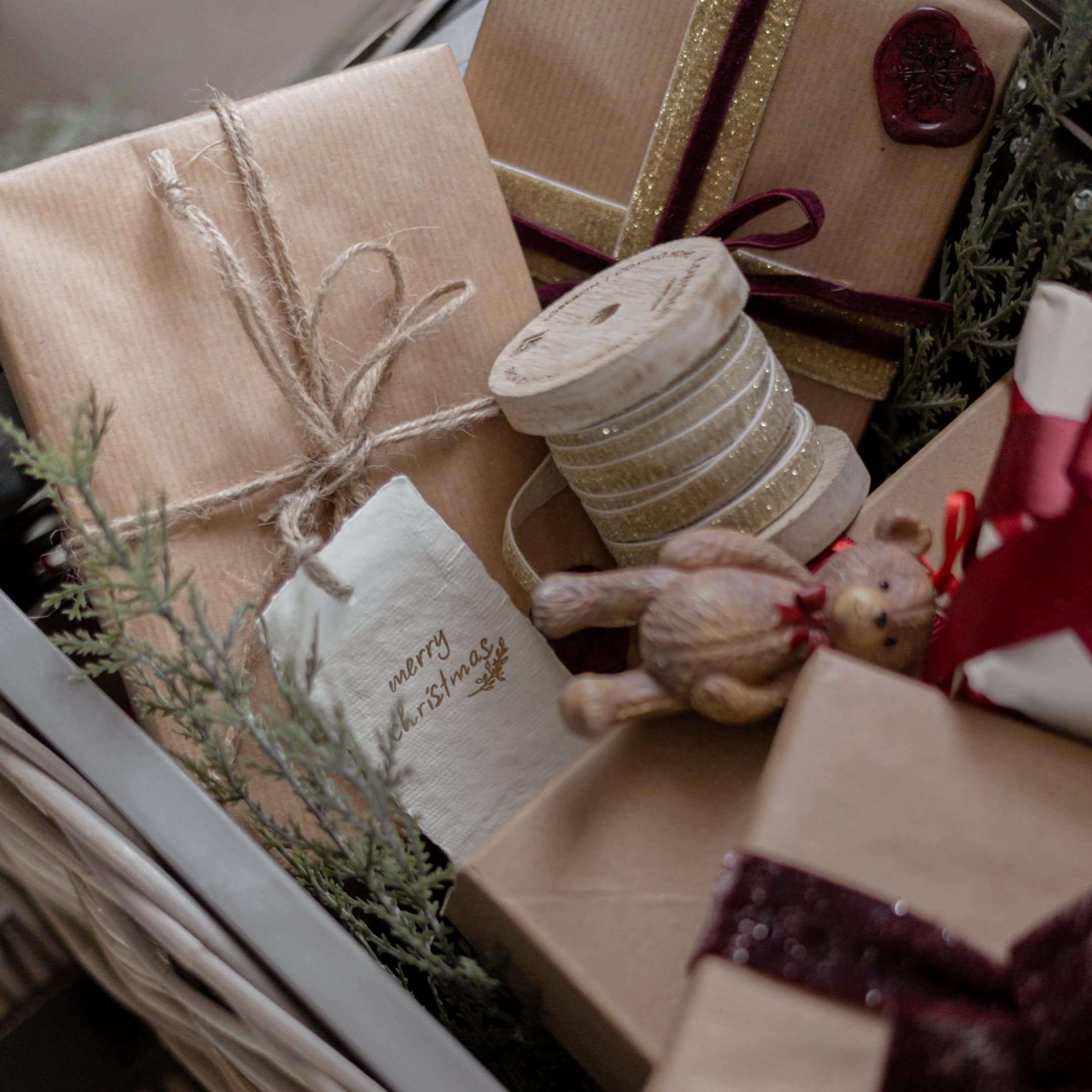 Weihnachtsgeschenke in braunem Packpapier mit dekorativen Bändern und Holzspule mit Glitzerrand