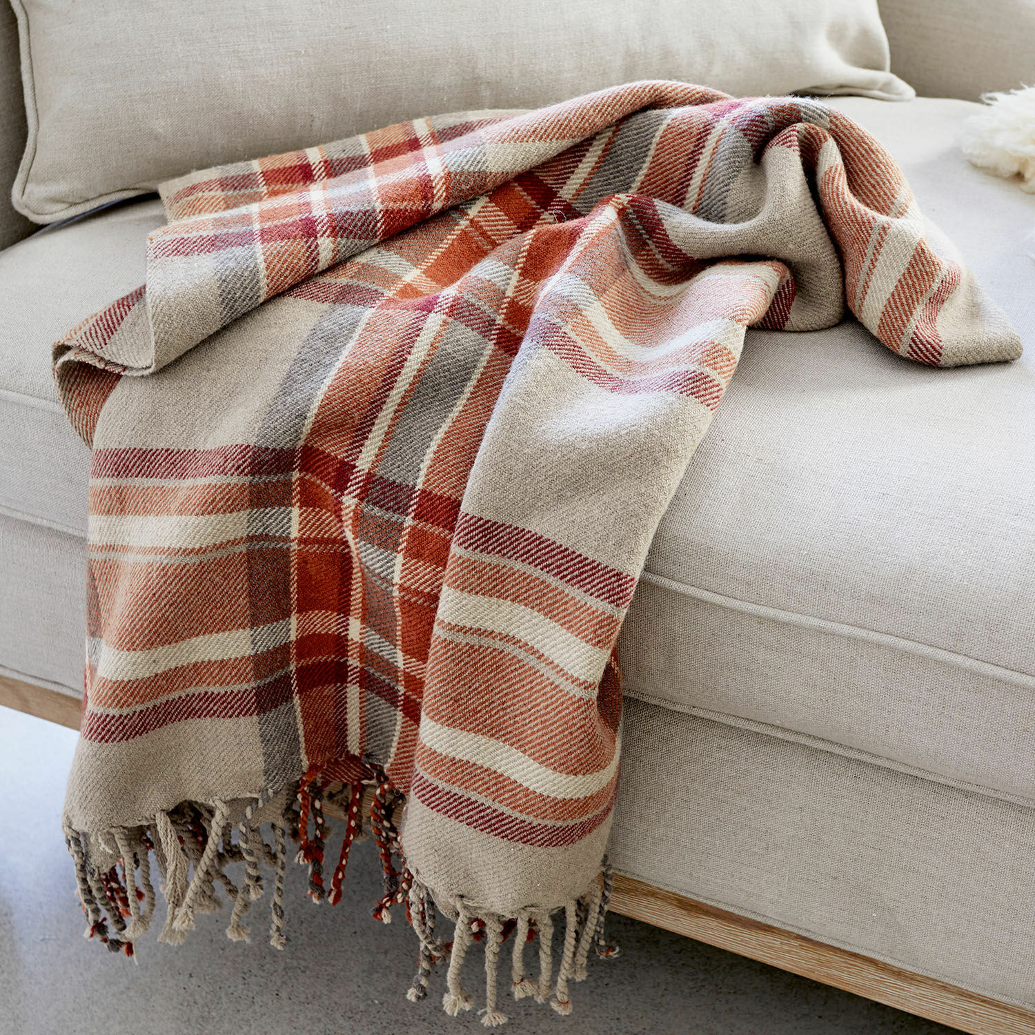 Plaid Tartan Weiche Baumwolldecke mit kariertem Muster in Beige und Rot auf hellem Sofa, Wohnaccessoire