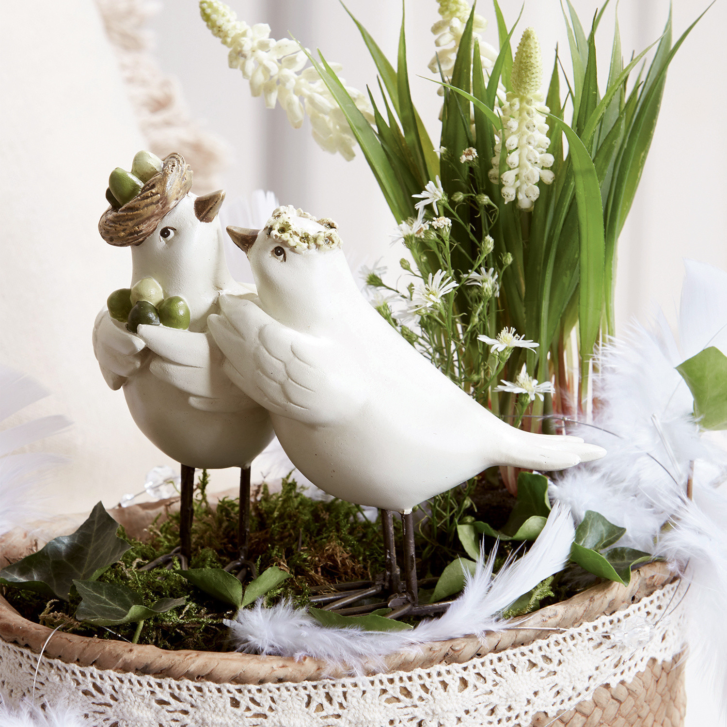 Vogelpaar Orne Weiße Deko-Vögel aus Keramik auf Metallfüßen in einem Korb mit Grünpflanzen und Blumen