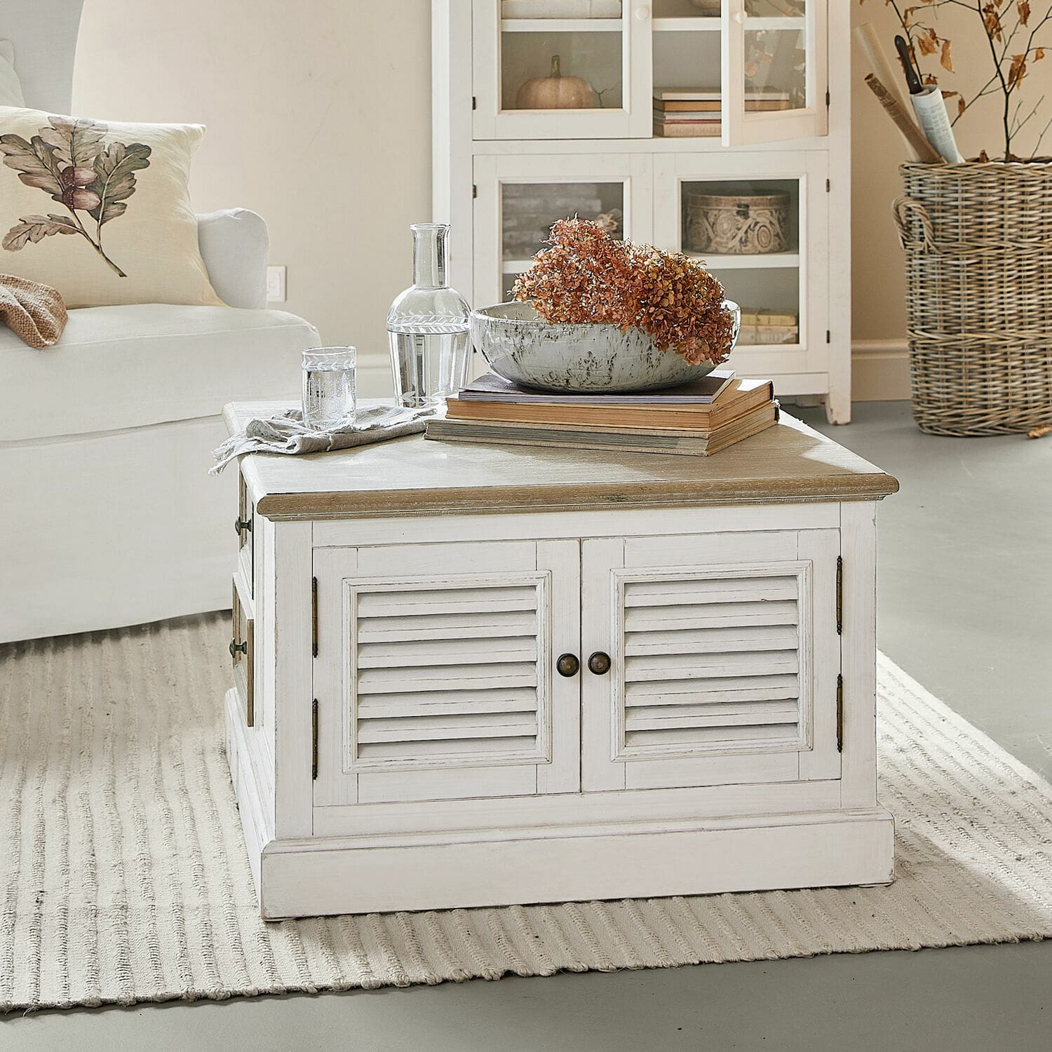 Couchtisch Cloverport Weißer Holzcouchtisch mit Schubladen und getrockneten Blumen als Dekoration im Wohnzimmer