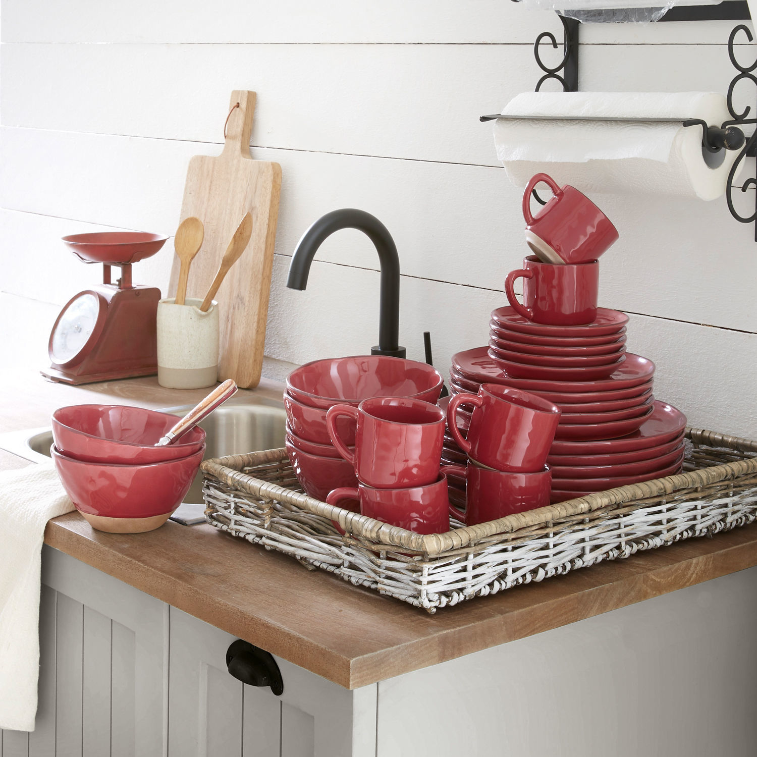 Rotes Keramik-Geschirrset mit Tassen, Tellern und Schalen auf Holzarbeitsplatte in Küche