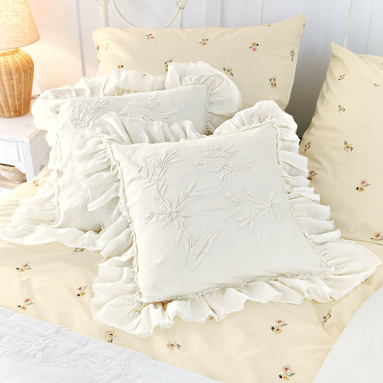 Beige Bettwäsche mit kleinem Blumenmuster und cremefarbene Leinenkissen mit Rüschen und Vogelstickerei