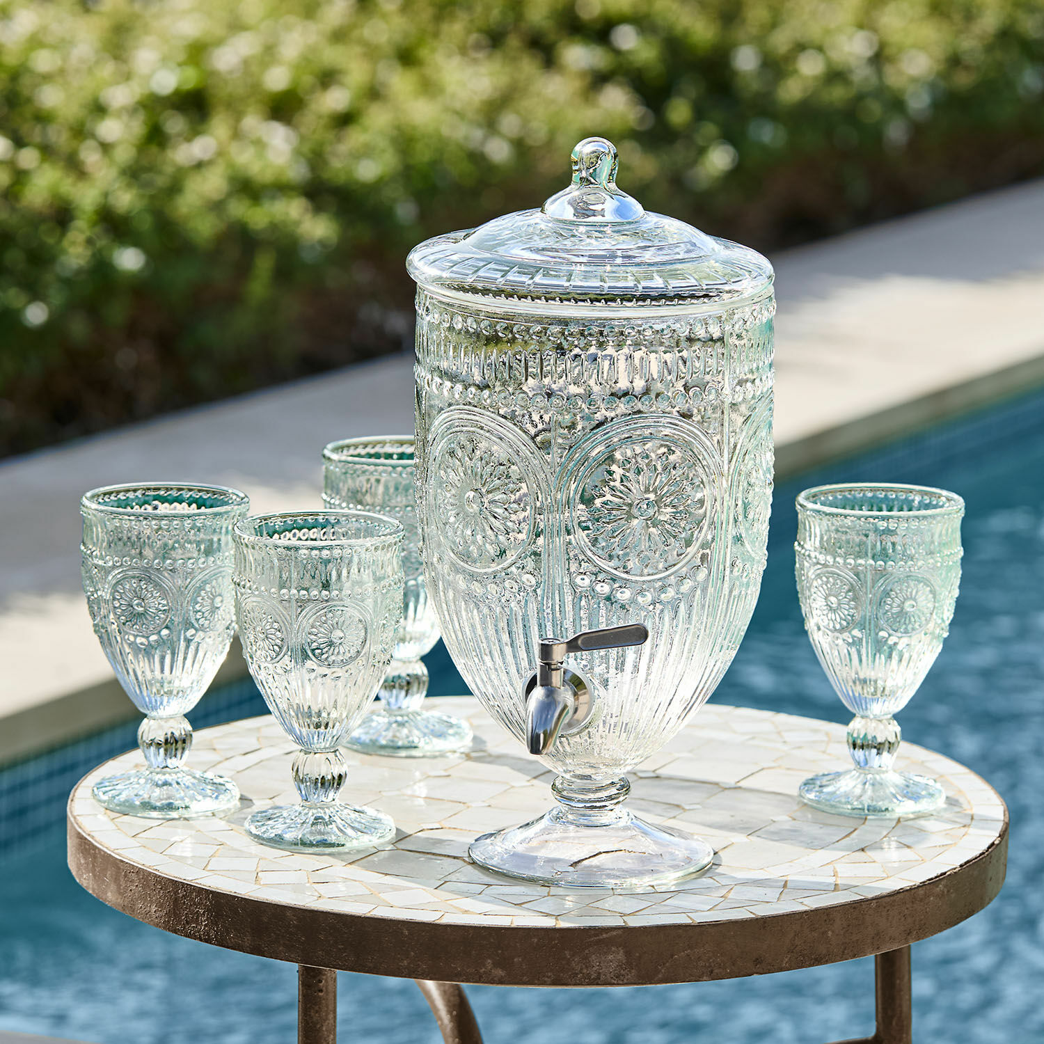 Getränkespender Mercure Glas-Getränkespender mit Deckel und Zapfhahn sowie vier passende Gläser auf Mosaiktisch am Pool