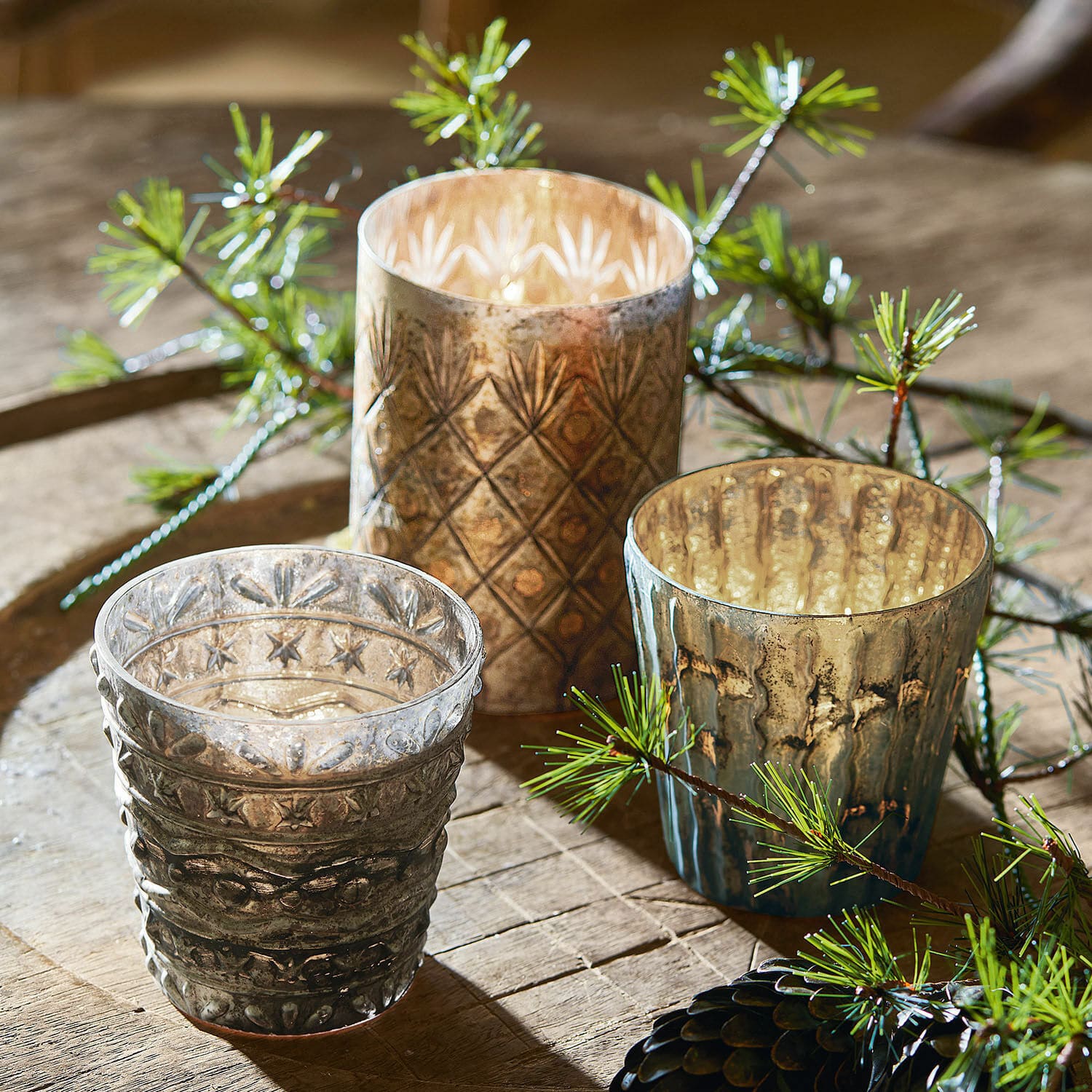 Windlicht 3er Set Ginai Drei dekorative Glas-Teelichthalter in Braun- und Grautönen mit Muster auf einem Holztisch