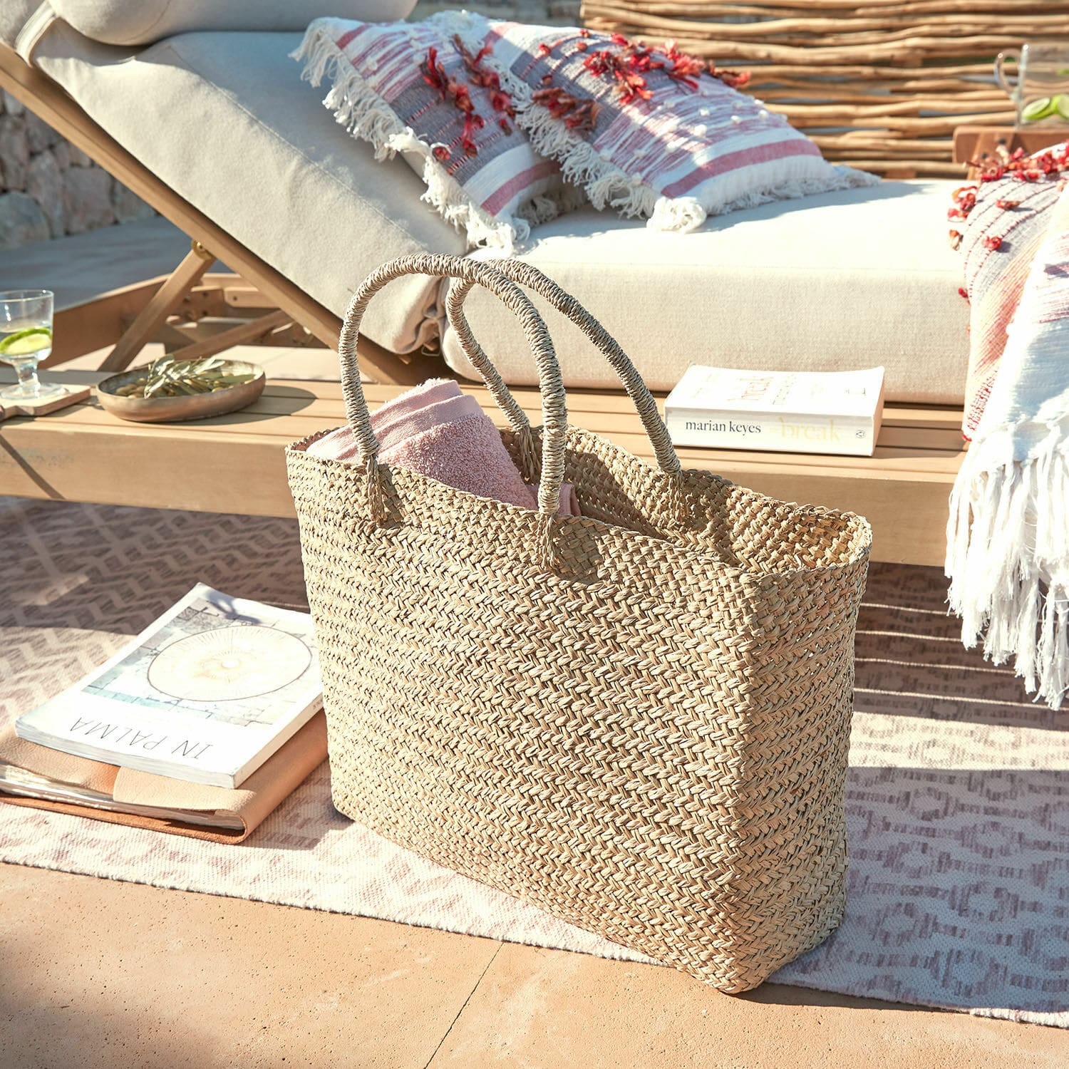 Tasche Ventresque Natürliche geflochtene Tasche aus Seegras mit rosa Handtuch auf Terrasse neben Liegestuhl