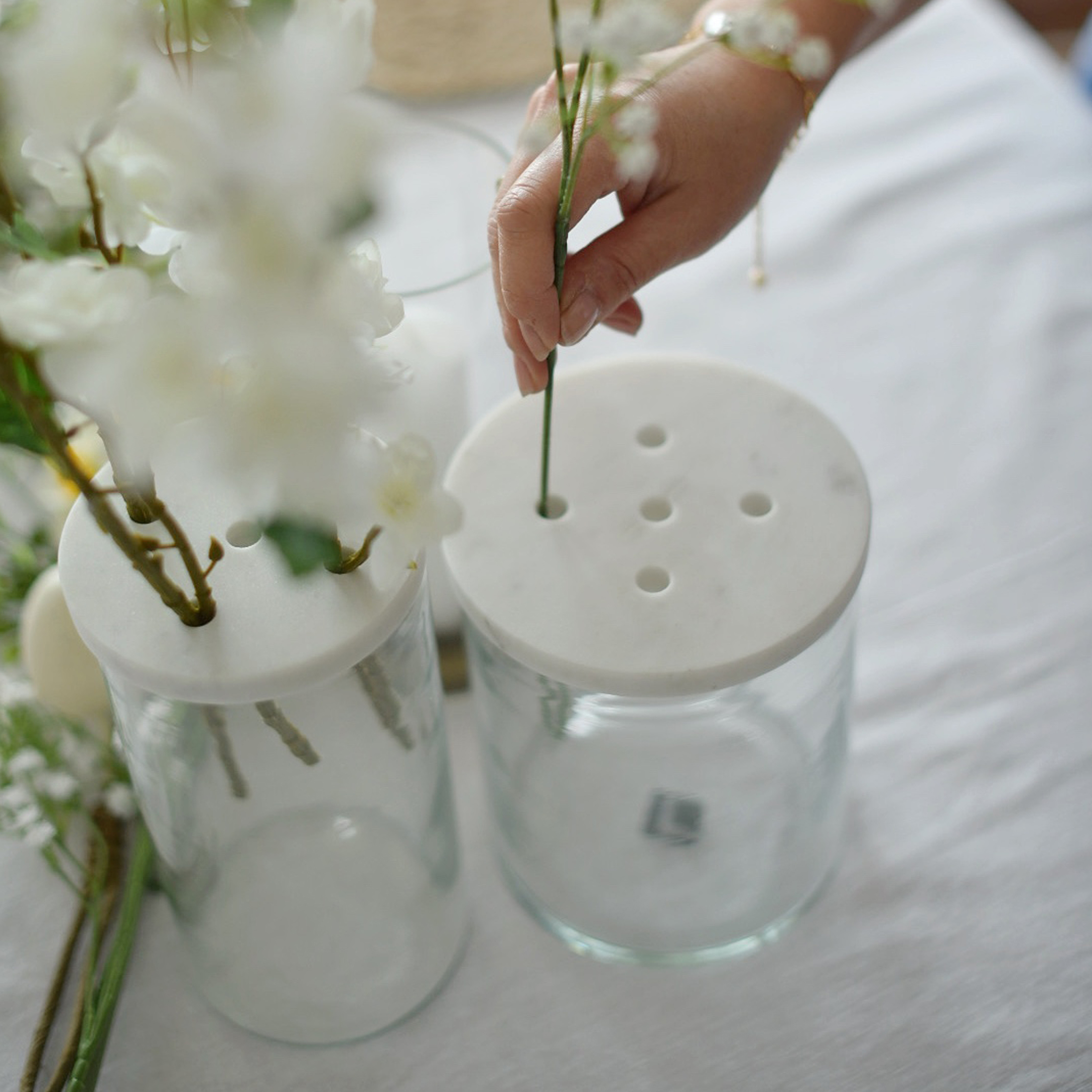 Glasvase mit weißem Marmordeckel und Löchern zum Arrangieren von Blumen auf dem Tisch