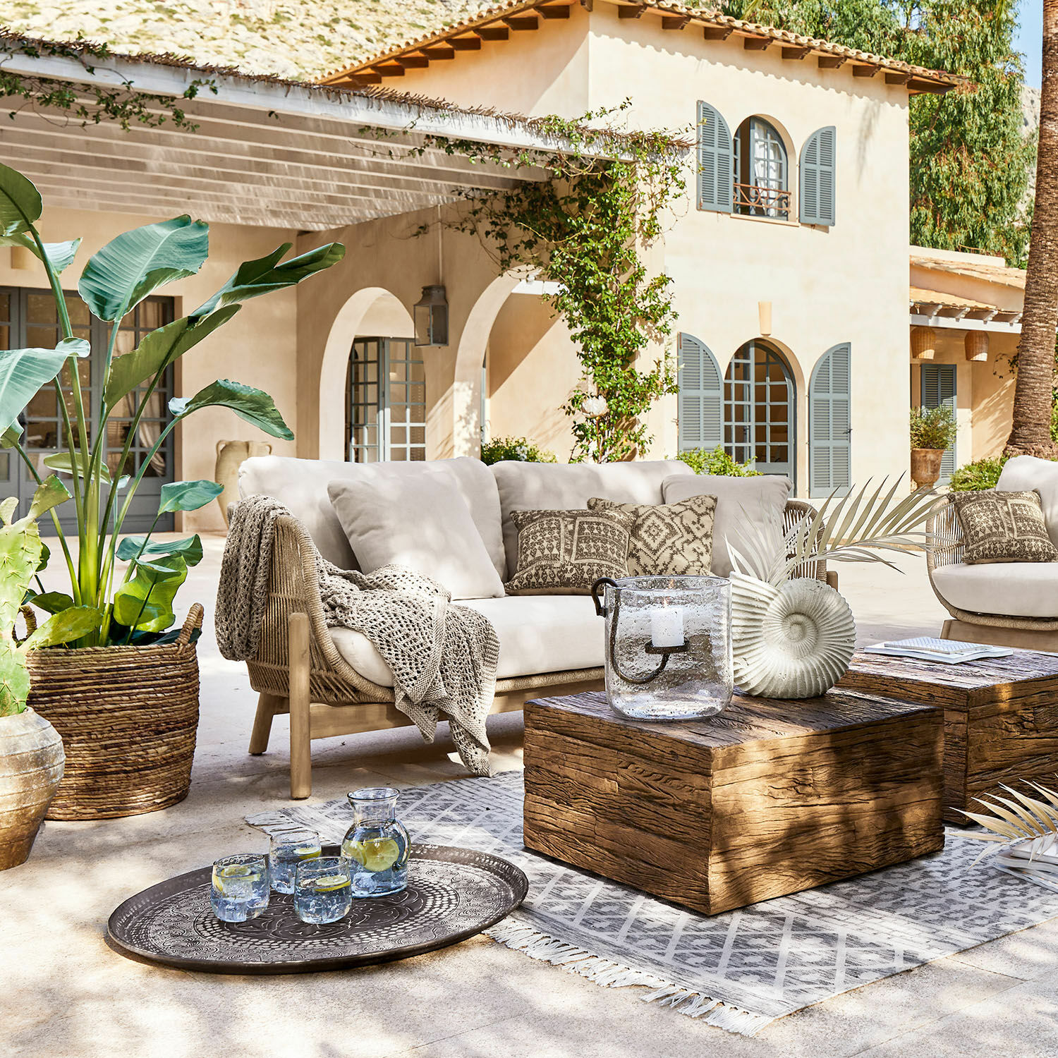 Sofa FSC®-100% Belvidere Outdoor-Möbelset mit beigem Sofa, Holztisch und Dekorationen auf sonniger Terrasse