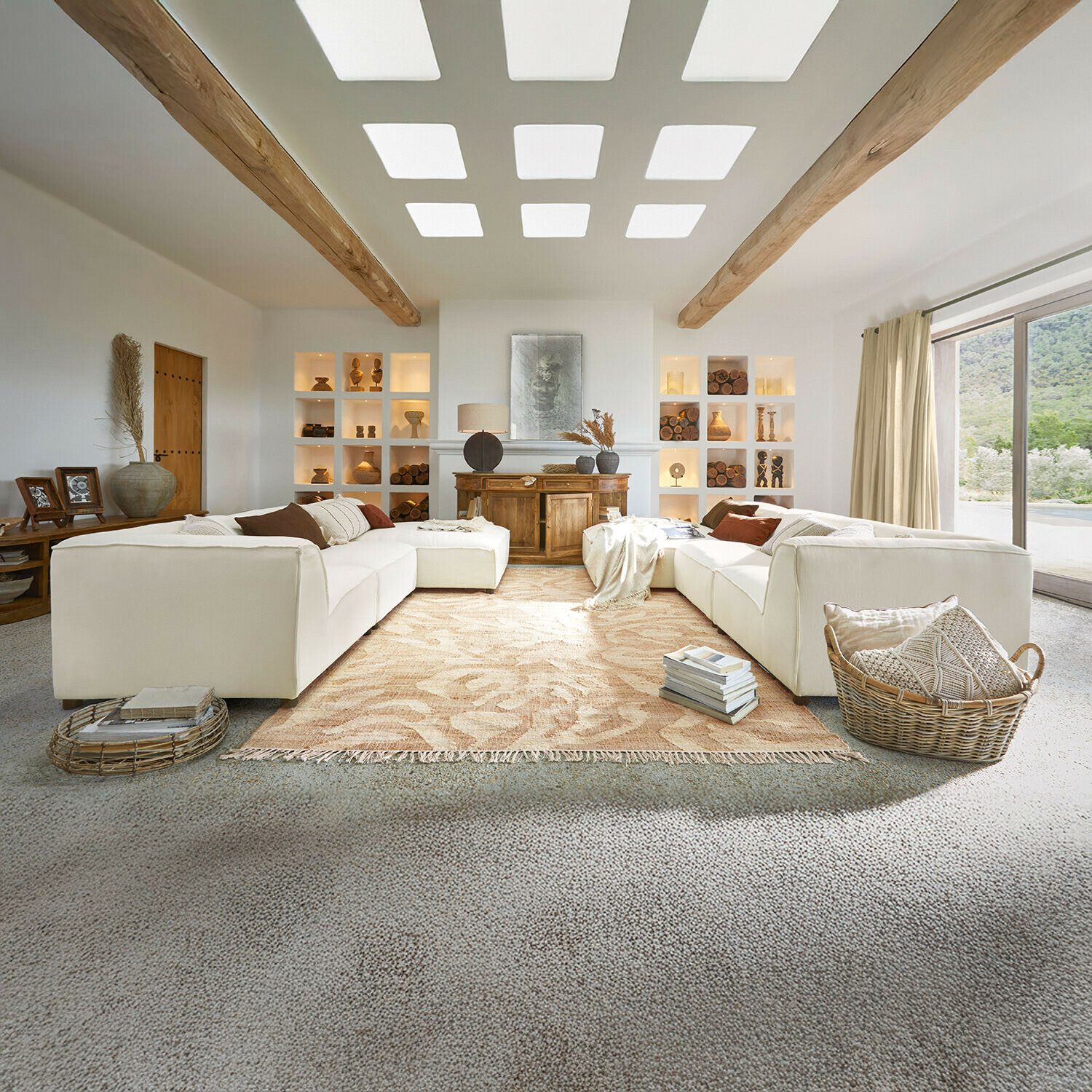 Sofa McLean Großzügiges Wohnzimmer mit weißem Sofa, Holzbalken, Naturdekorationen, beigem Teppich und großem Fenster