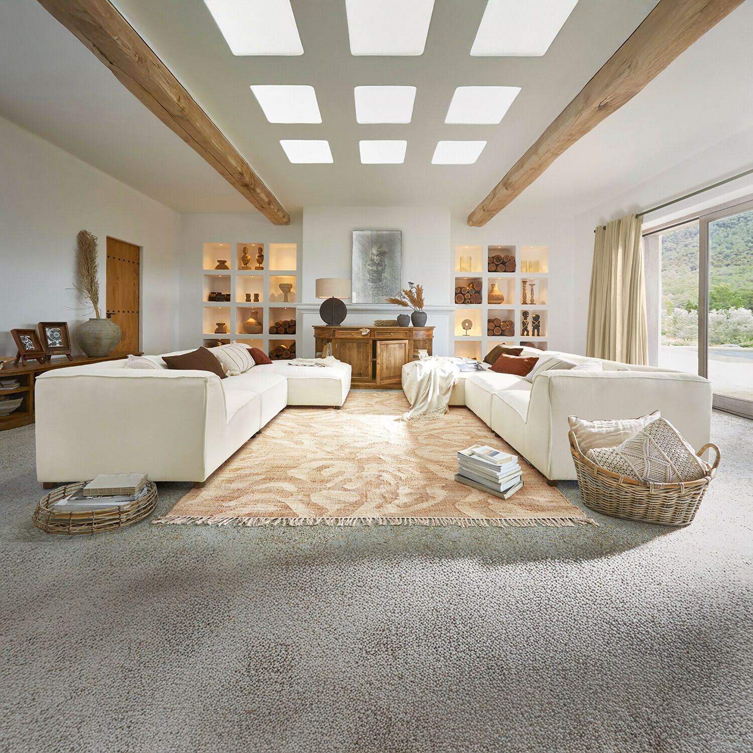 Sofa McLean Großzügiges Wohnzimmer mit weißem Sofa, Holzbalken, Naturdekorationen, beigem Teppich und großem Fenster