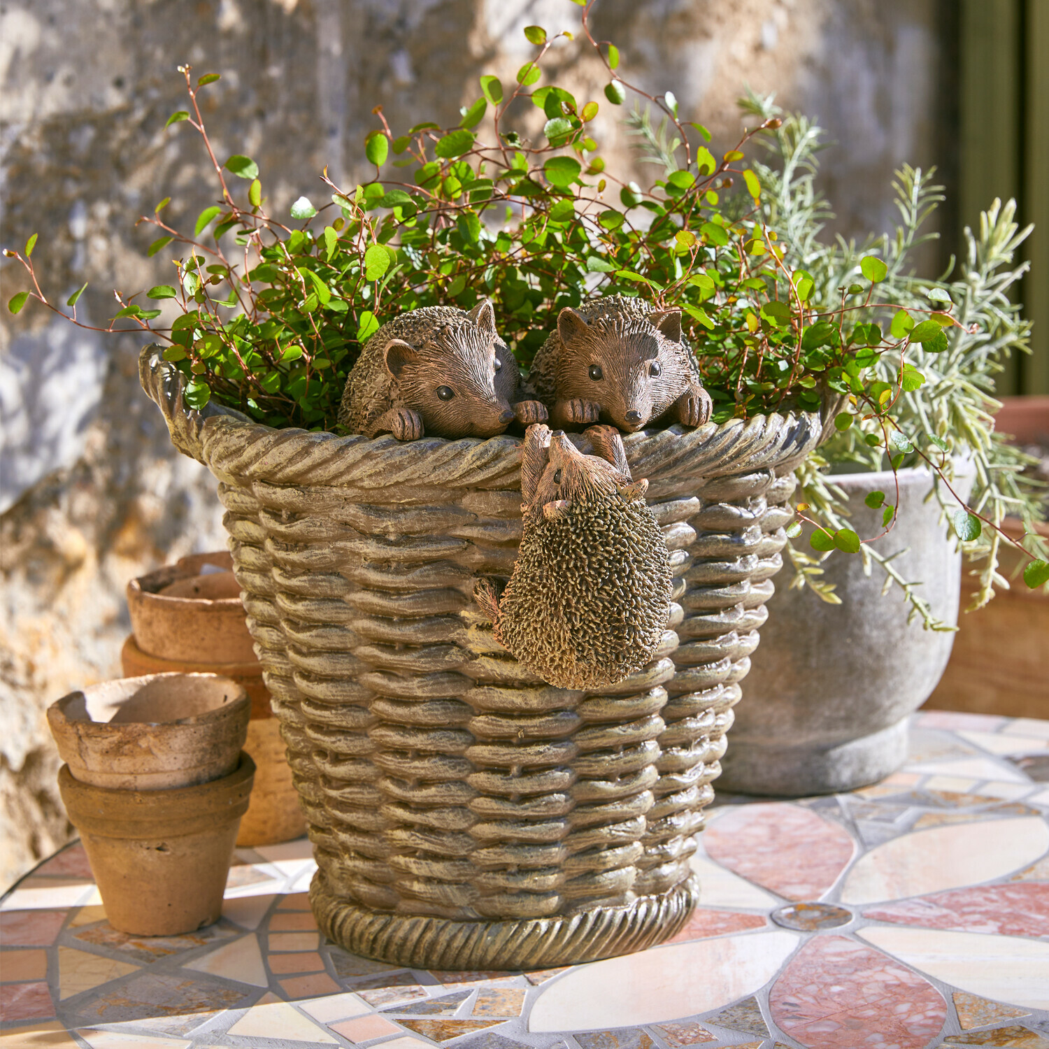 Übertopf Gabriel Grauer Kunststoff-Blumentopf mit Igel-Dekor und grünen Pflanzen auf Mosaik-Terrasse