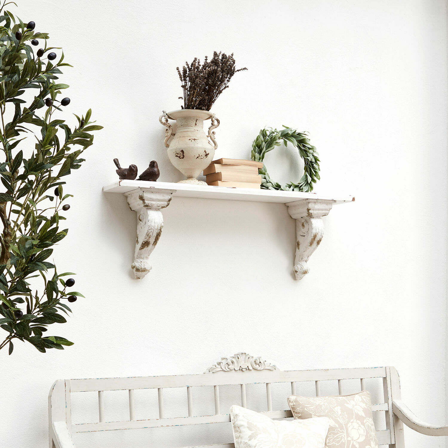 Weiße Holz-Wandregal mit dekorativem Halter, Vase, Büchern und grünem Kranz