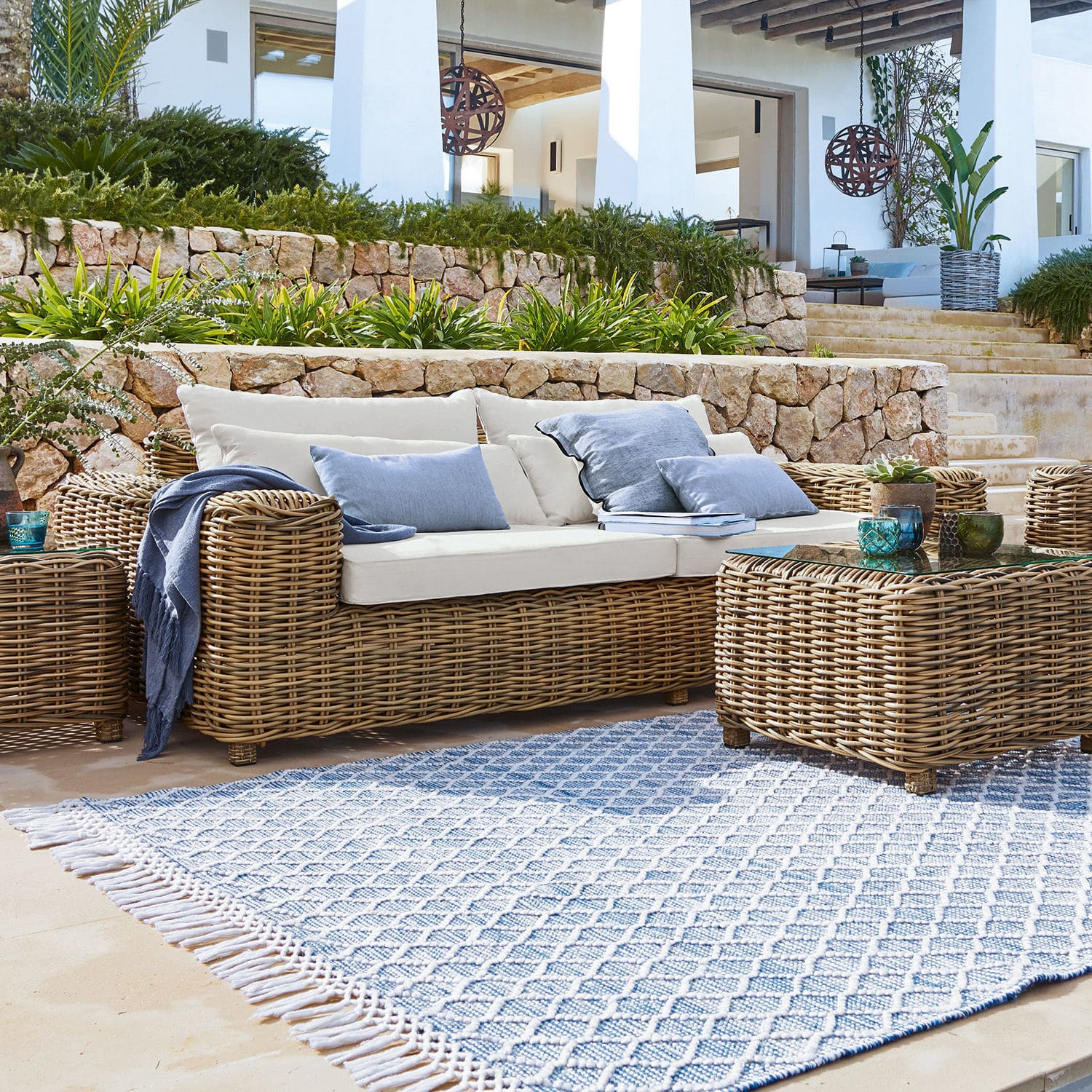 Sofa Camas Gartenmöbel-Set aus natürlichem Rattan mit cremefarbenen Kissen und blauem gemustertem Teppich