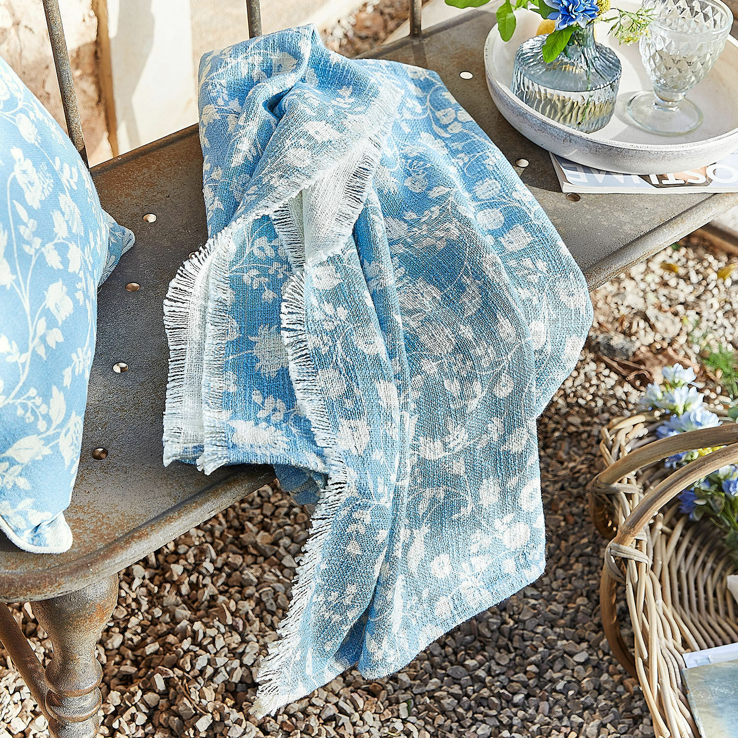 Plaid Corvelique Blaues Baumwollplaid mit weißem Blumenmuster auf Metallbank im Garten drapiert