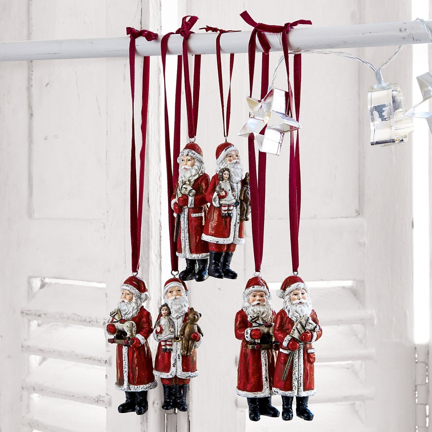 Set aus roten Weihnachtsmann-Dekorationen aus Material an bordeauxroten Bändern hängend, Weihnachtsdeko