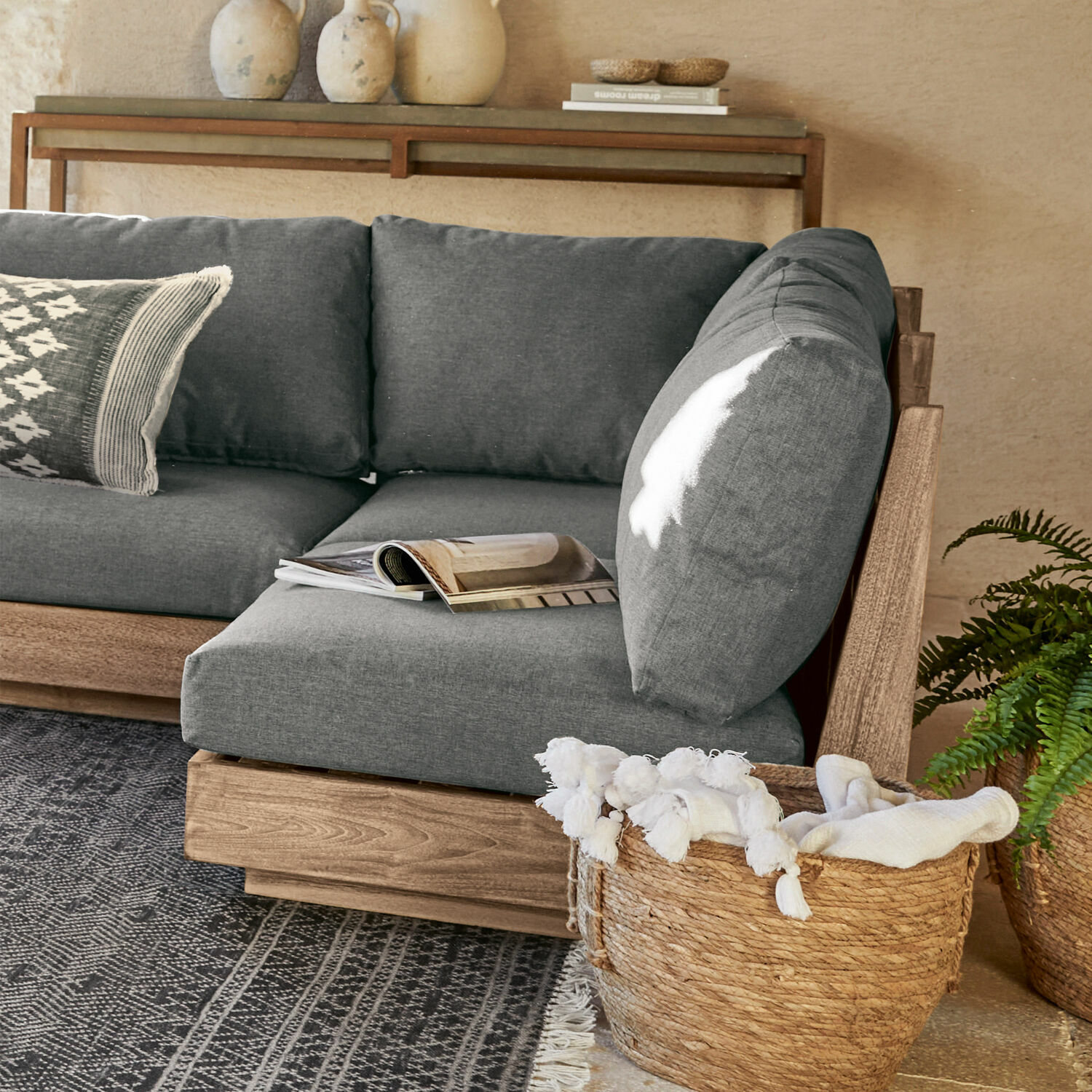 Sofaelement Courtelevant Graues Sofa mit Holzrahmen und weichen Kissen in modernem Wohnzimmer mit Korb aus Weide