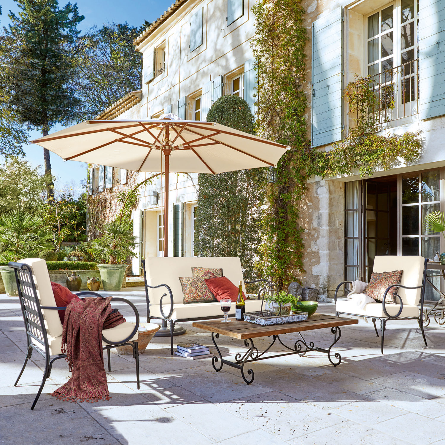 Sitzgruppe Massana Gartenmöbel-Set mit Metallrahmen und cremefarbenen Polstern auf Stein-Terrasse mit Sonnenschirm